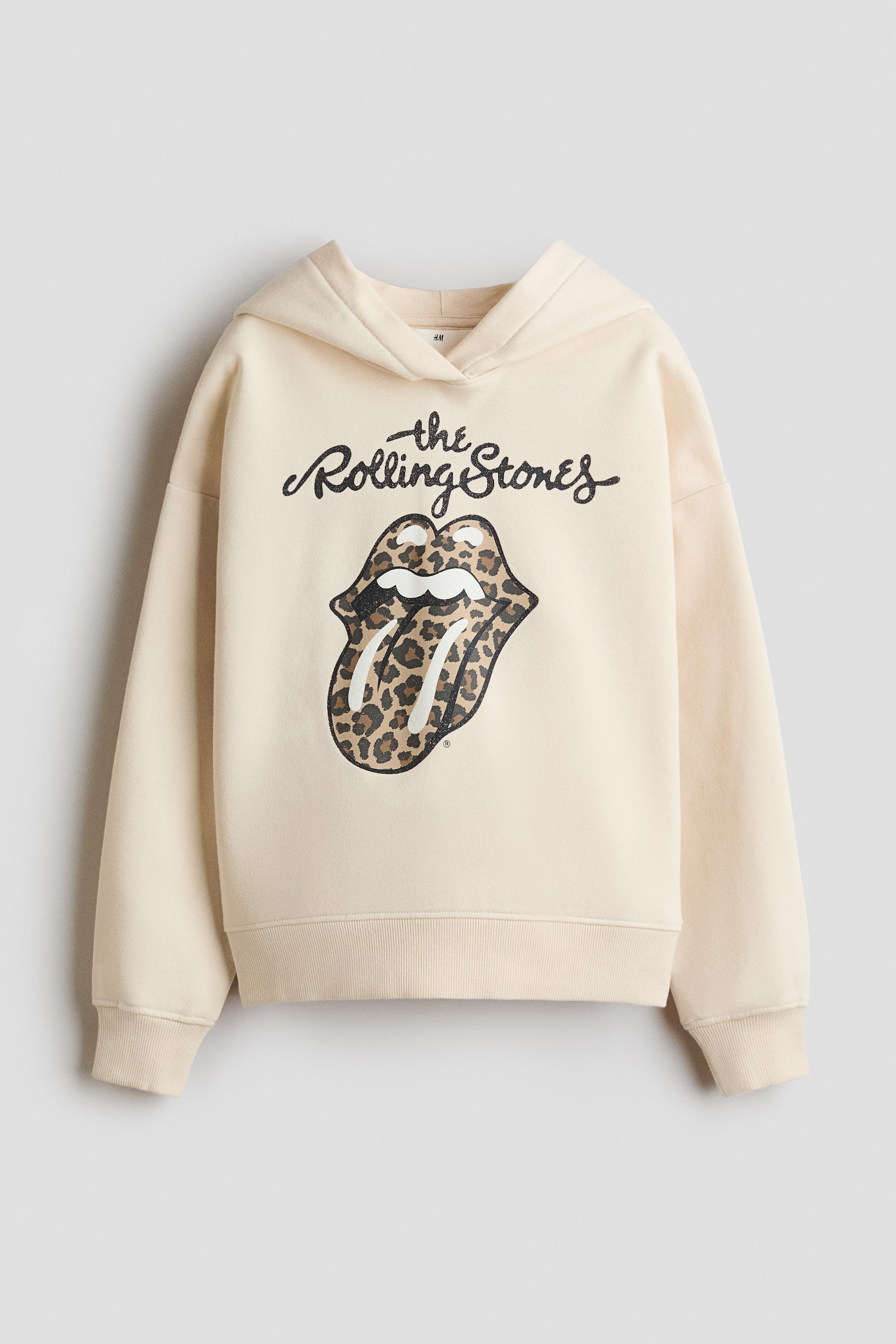 View larger image: A cream hoodie is showcased from the front, featuring a black "the Rolling Stones" text and a leopard print tongue and lips logo on the chest. It is crafted with long sleeves, ribbed cuffs, and a ribbed hem.