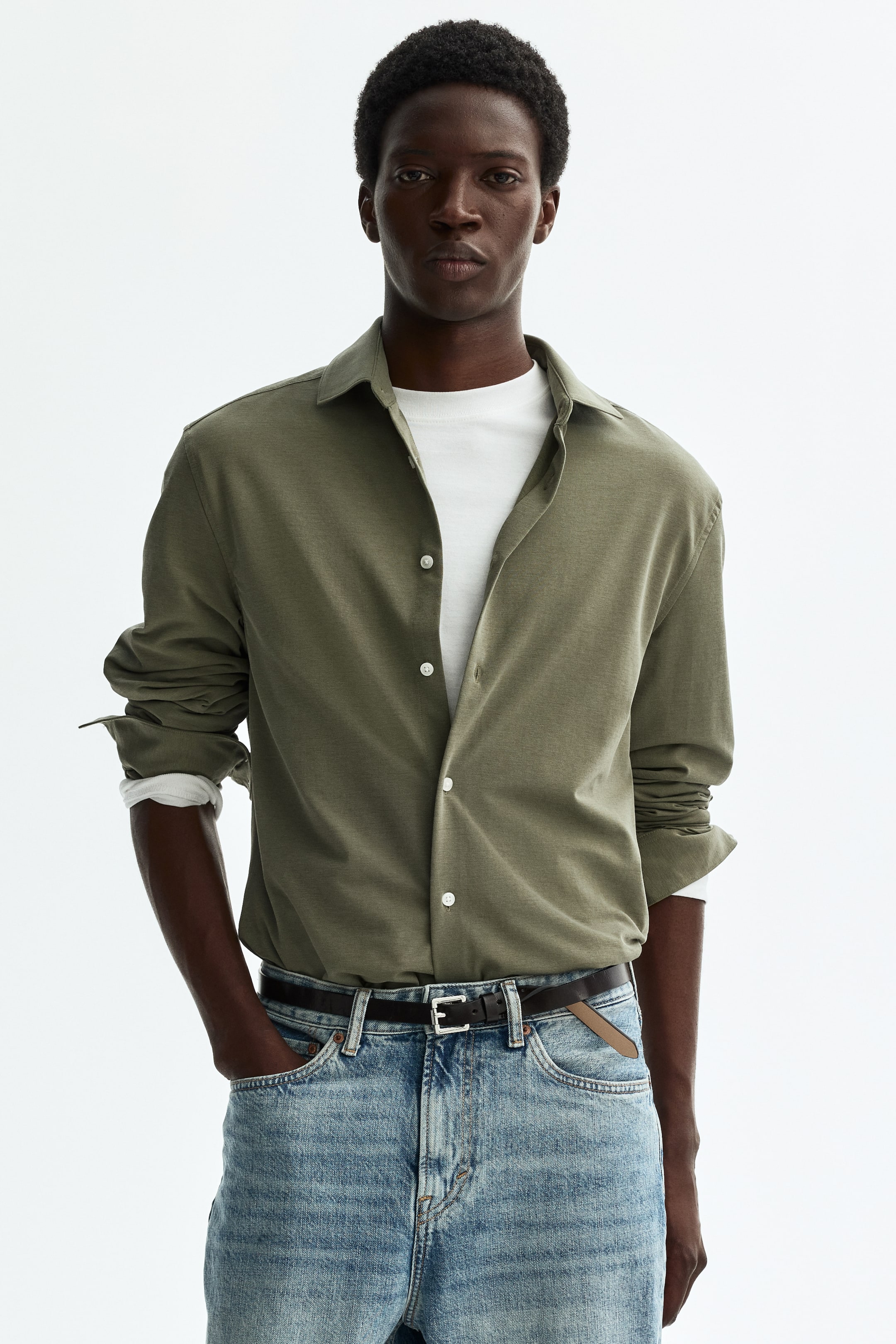 View larger image: An olive green button-up shirt crafted from a soft fabric is showcased from the front, styled open over a white crew-neck t-shirt. The long sleeves are rolled up, and the white buttons are prominently displayed on the front placket.