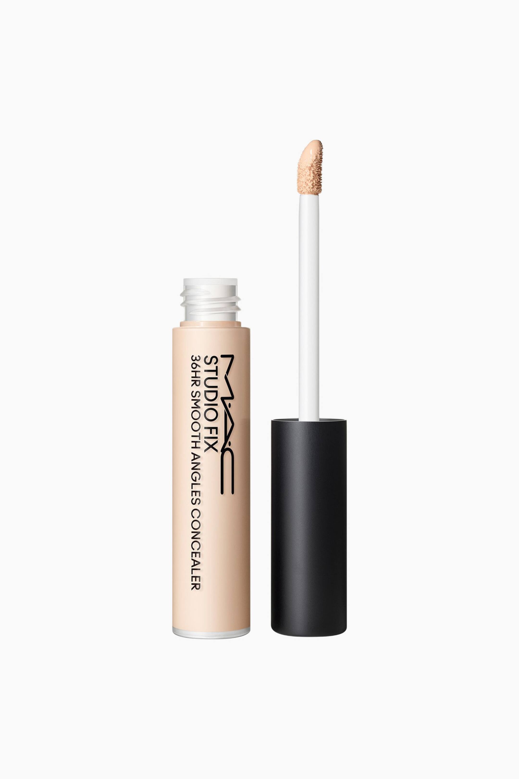 Se større billede: MAC Studio Fix 36HR Smooth Angles Concealer præsenteres med sin lyse beige tube vendt fremad, hvor produktnavnet vises vertikalt på siden. Dens sort-hætte applikator er trukket ud, og viser en hvid stav med en doe-foot spids dækket af lyse beige concealer.