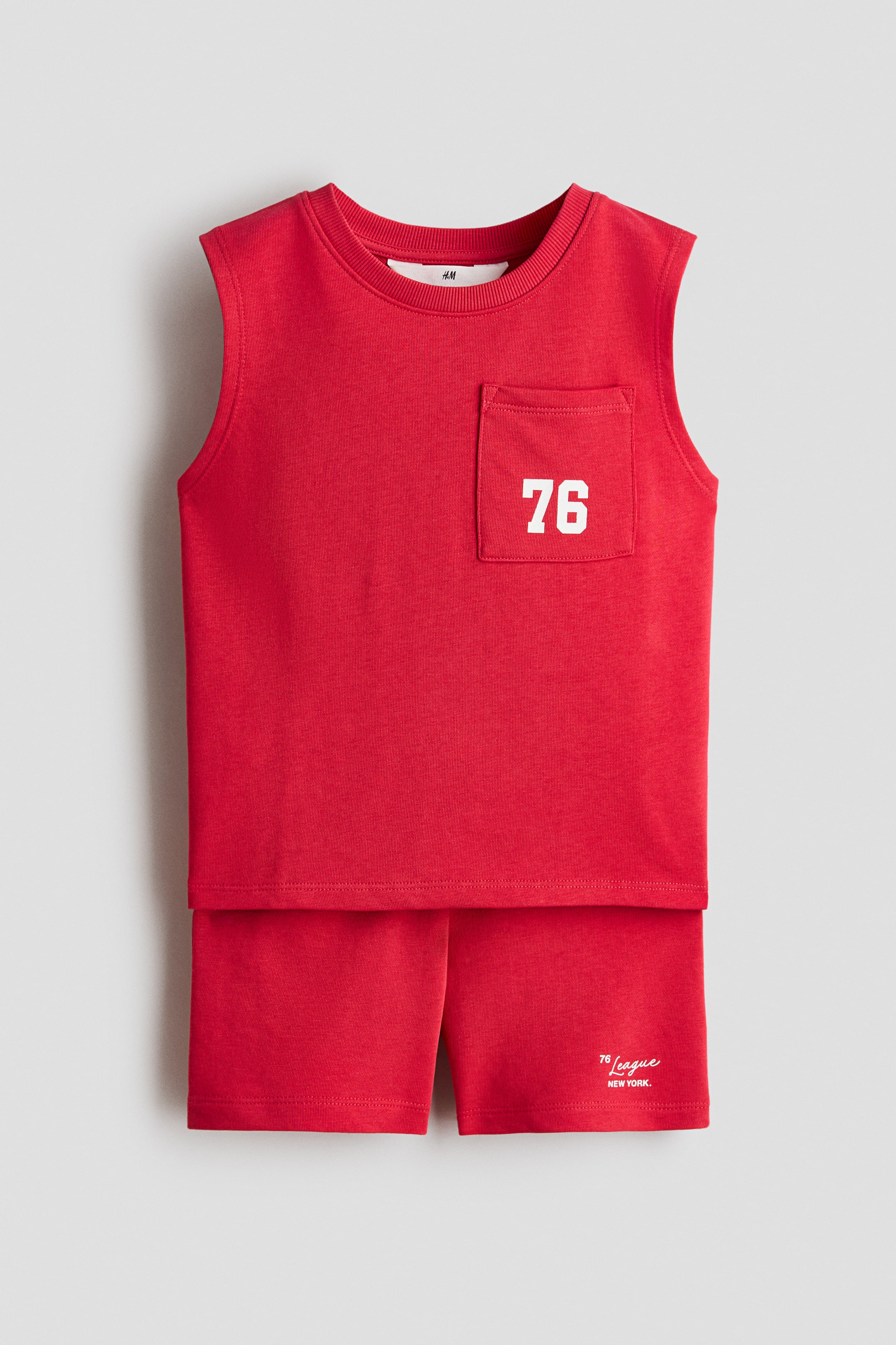 View larger image: A red two-piece set is showcased from the front, comprising a sleeveless top and shorts. The top is designed with a ribbed crew neck and a patch pocket on the left chest, featuring "76" in white print. The shorts display "76 League NEW YORK." in white script on the lower left leg.
