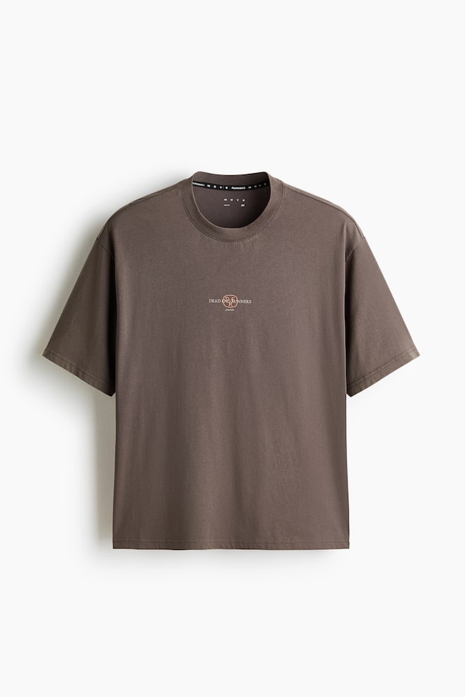 A dark brown, boxy-style sports T-shirt is displayed from the front. It features a crew neck, short sleeves, and a small circular logo with "DEAD RUNNERS" text on the chest. - 1
