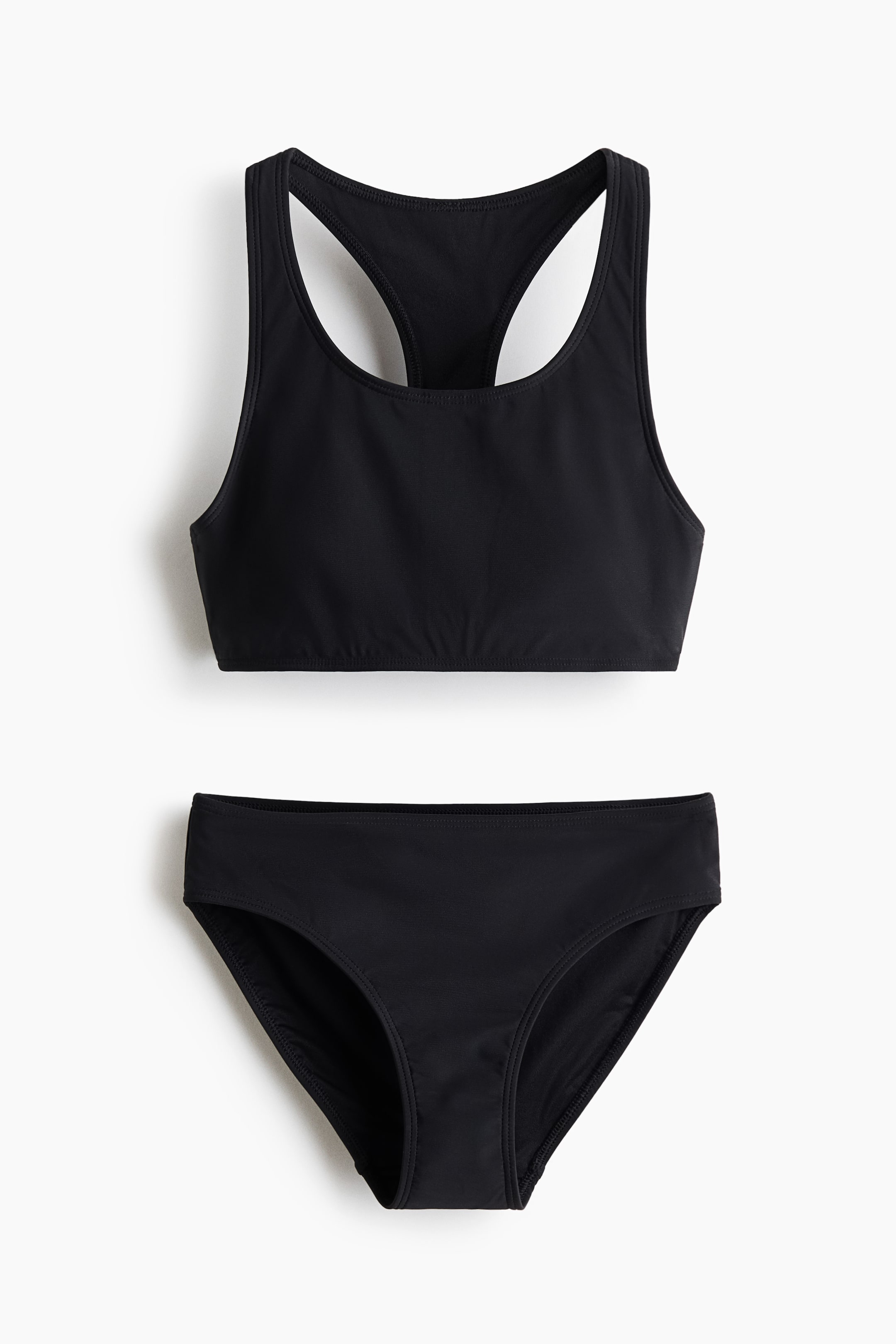 Visa större bild: Ett svart tvådelat baddräkt ligger plant. Toppen är en racerback-stil bikiniöverdel med en rundad halsringning, och botten är en matchande bikinibyxa.