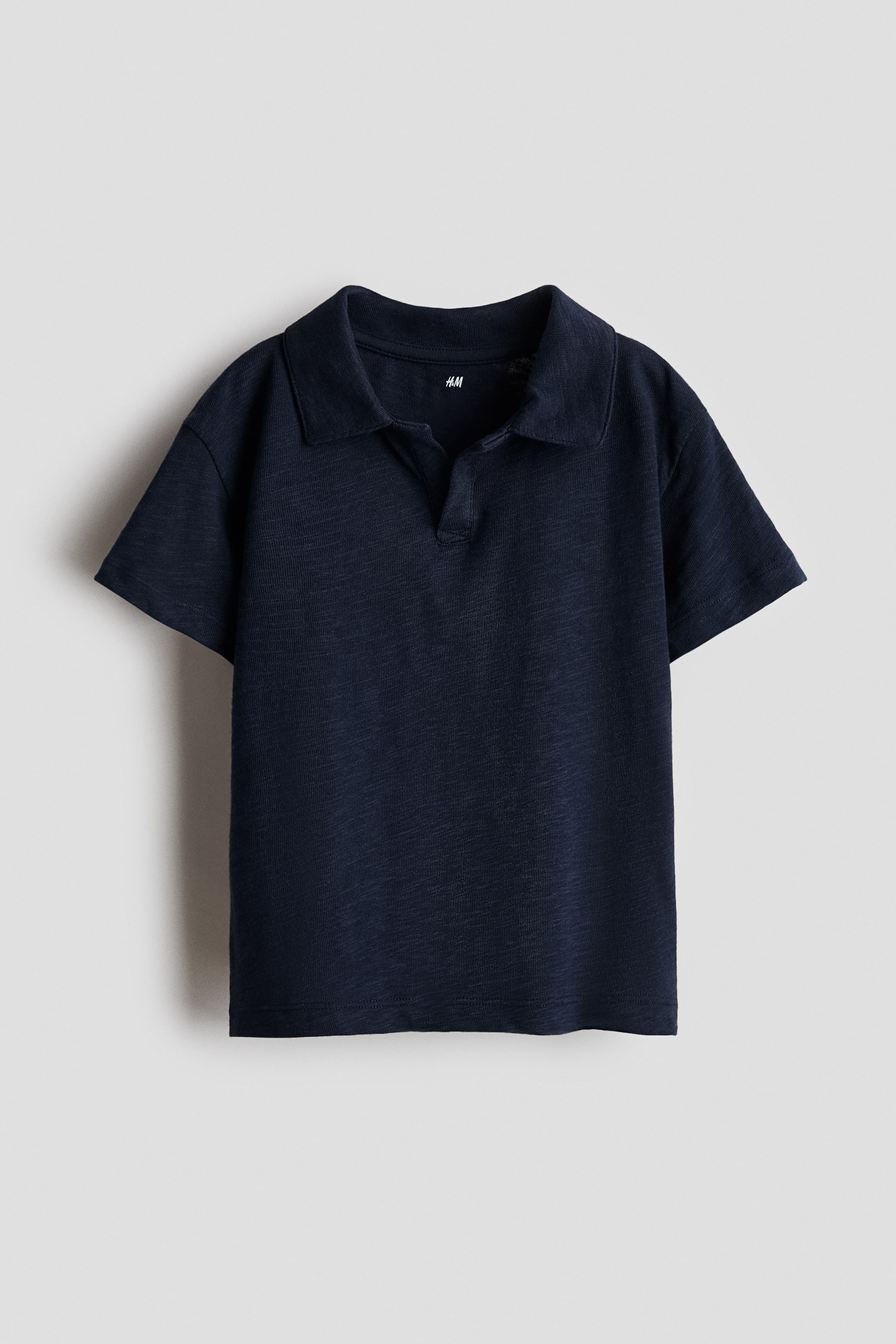 View larger image: A dark blue polo shirt is presenting its front view, featuring a spread collar, a V-neck placket, short sleeves, and a textured knit fabric.