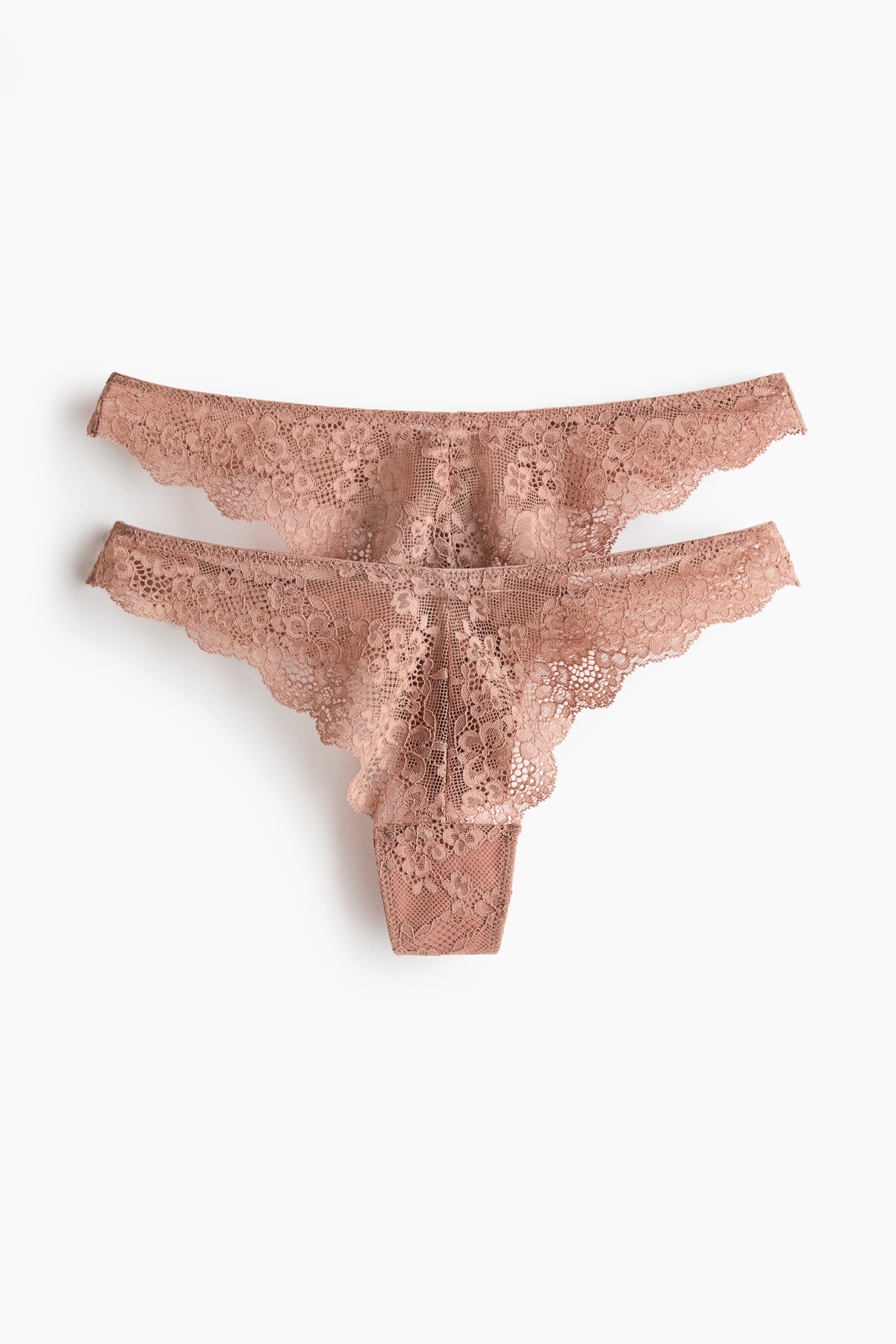 View larger image: Two light brown lace thongs are laid flat, facing FRONT, with one thong slightly overlapping the other. Each thong showcases a floral lace pattern and scalloped edges along the waist and leg openings.