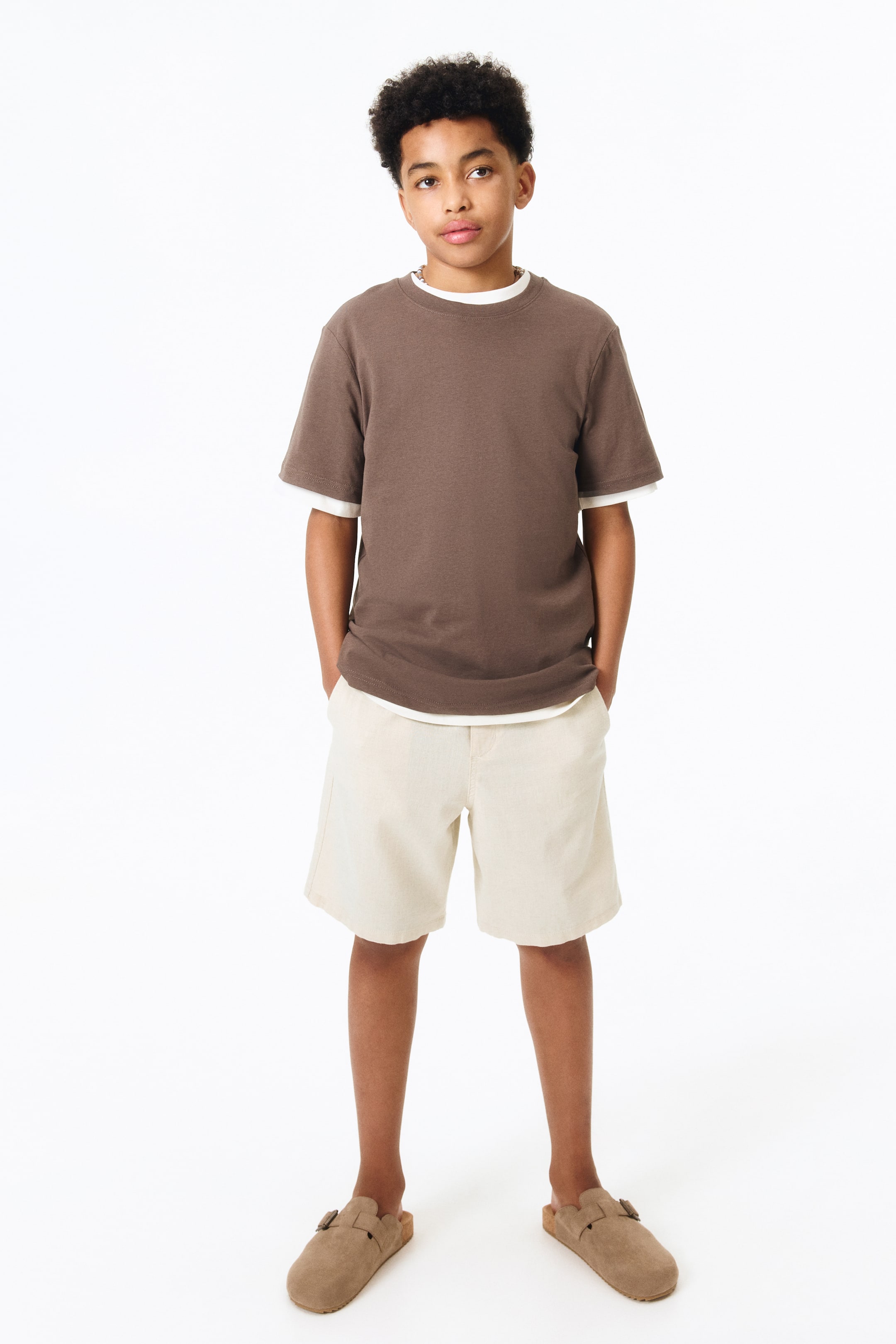 View larger image: Light beige cotton and linen blend shorts feature an elastic drawstring waistband, faux fly, and diagonal front pockets. Displayed from the front.