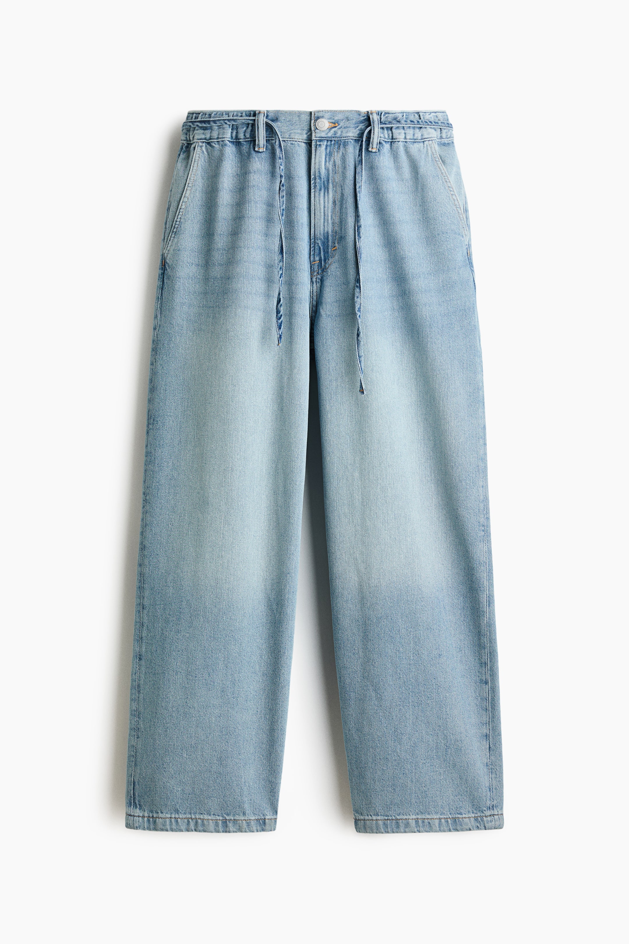 View larger image: Light blue denim trousers are displayed from the front, featuring an elasticized waistband with belt loops, a drawstring, a button closure, and a zipper fly. The wide-leg trousers showcase a faded wash, appearing lighter on the upper thighs and gradually darkening towards the straight hems.