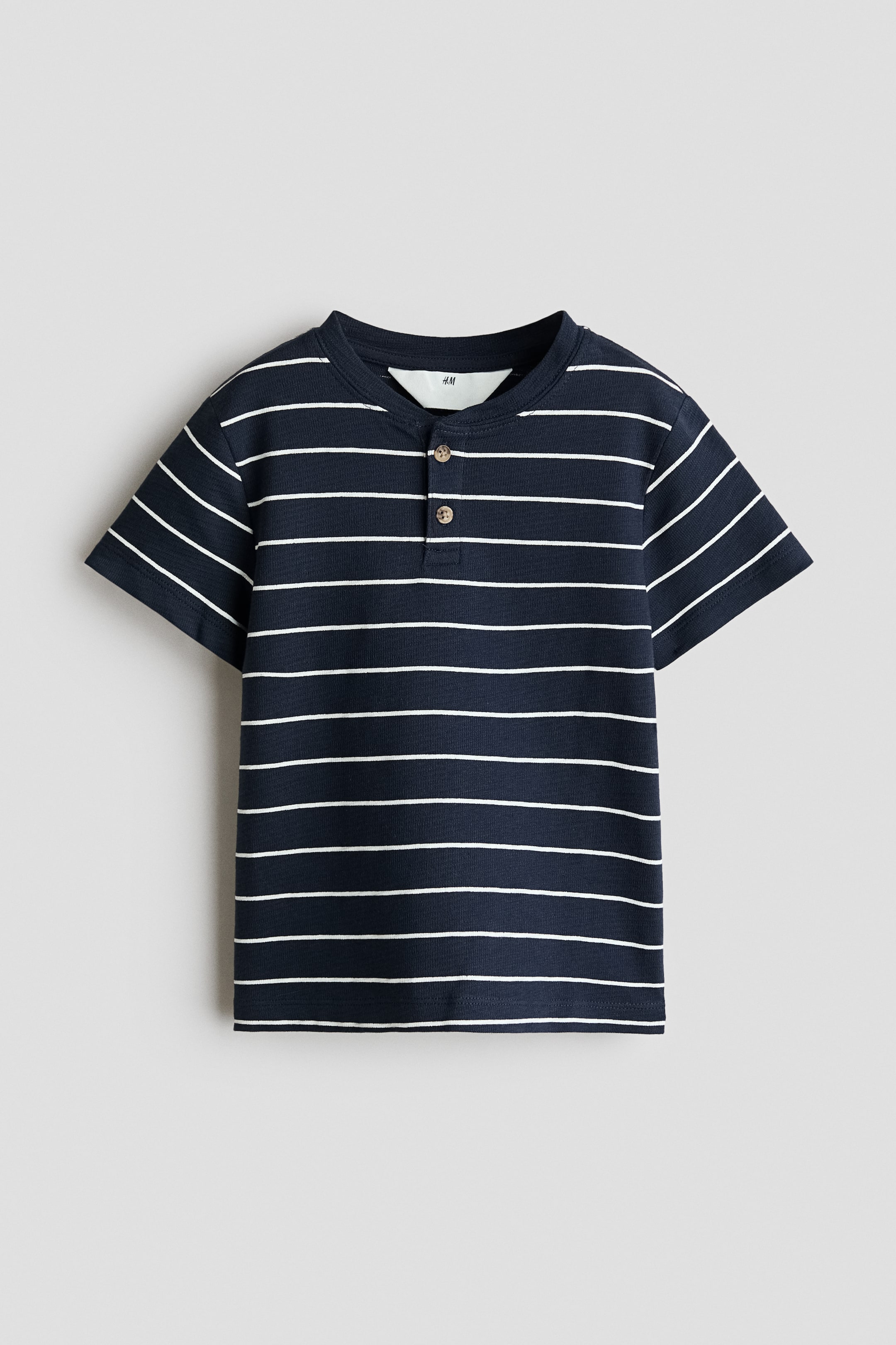 View larger image: A dark blue Henley t-shirt showcases white horizontal stripes across its body and short sleeves. It features a round neck and a two-button placket with wooden buttons at the front.