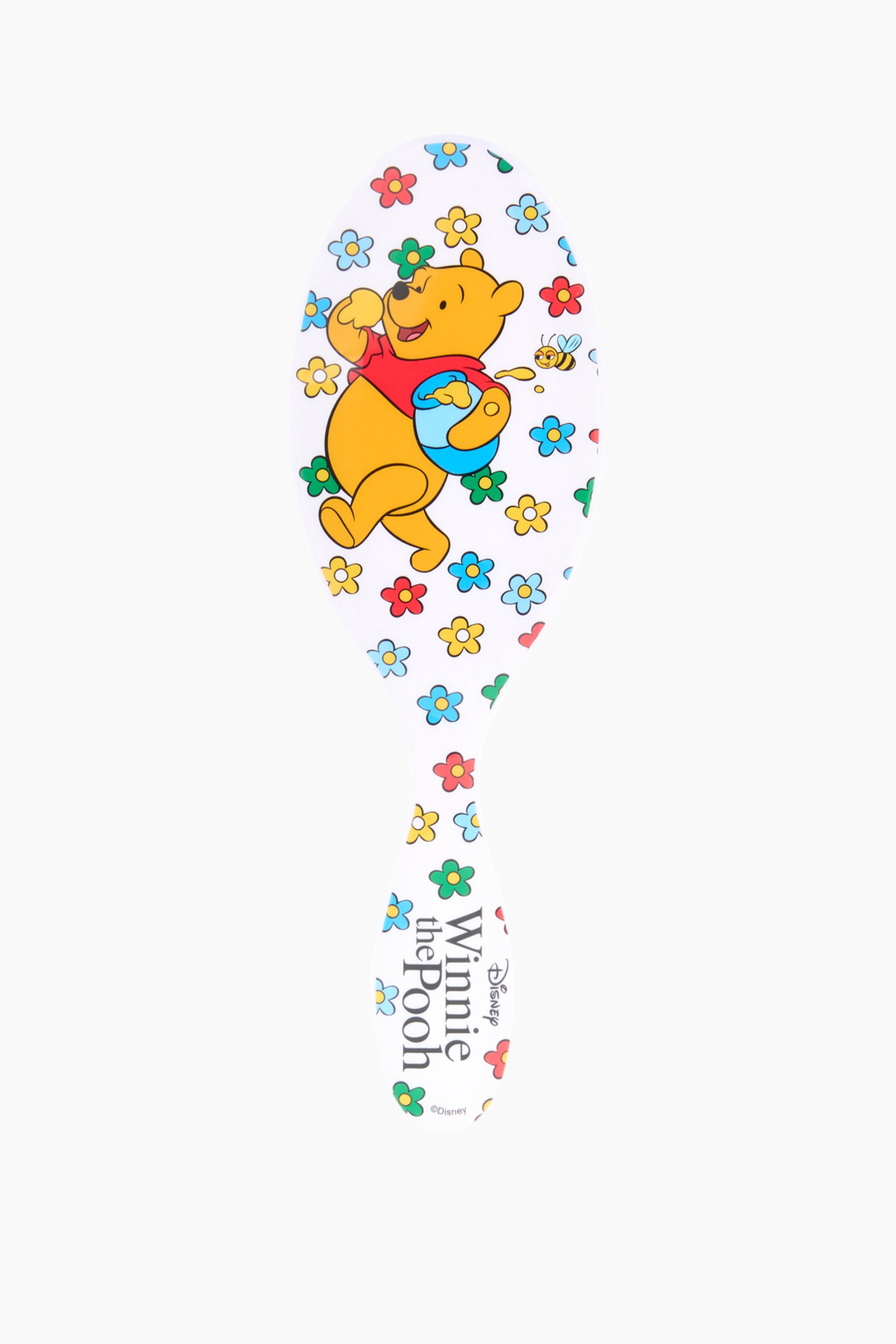 Größeres Bild ansehen: Eine weiße, ovalförmige Paddle-Haarbürste mit einem verjüngten Griff steht aufrecht und blickt nach vorne. Auf ihrer Oberfläche befindet sich eine bunte Illustration von Winnie Puuh, der ein rotes Hemd trägt und einen blauen Honigtopf hält, umgeben von kleinen roten, blauen, gelben und grünen Blumen und einer Biene, mit dem Text "Winnie the Pooh" sichtbar am unteren Griff.