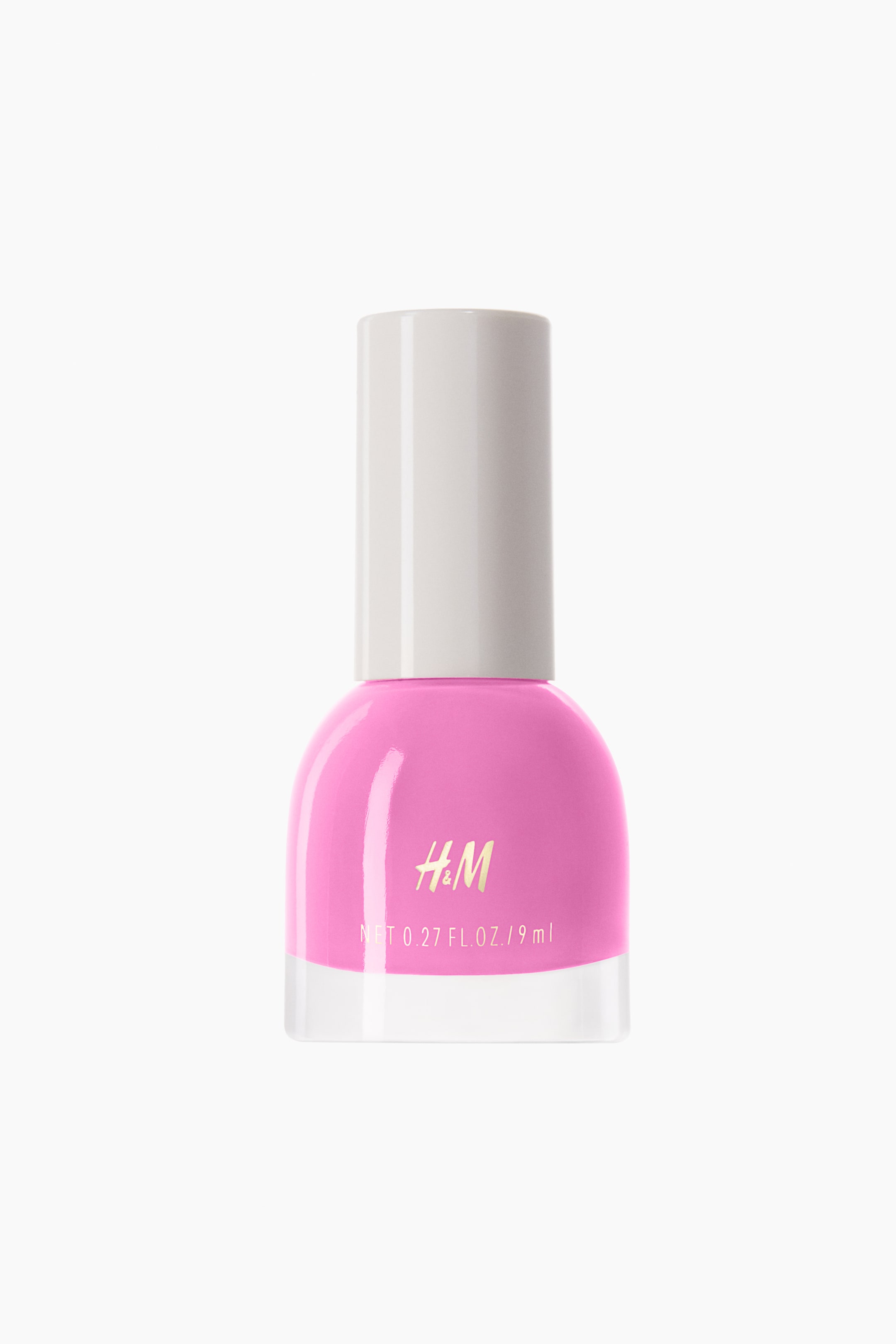 View larger image: The nail polish bottle showcases a vibrant pink hue, encased in a rounded transparent glass container, finished with a white cylindrical cap. The front of the bottle prominently features the gold "H&M" logo alongside the text "NET 0.27 FL. OZ. / 9 ml."