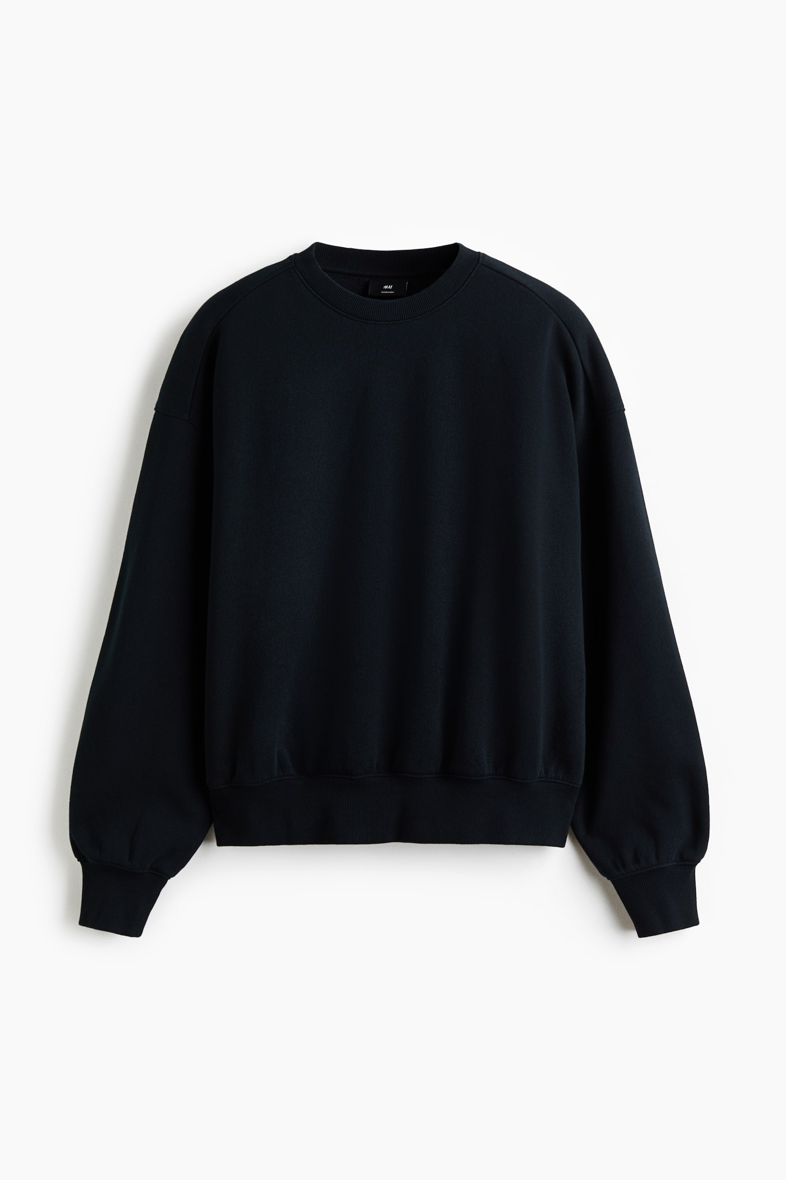 A black crew neck sweatshirt is shown with a relaxed fit, dropped shoulders, and long, full sleeves. The sweatshirt features a ribbed neckline, ribbed cuffs, and a matching ribbed hem in a straight front-facing view.