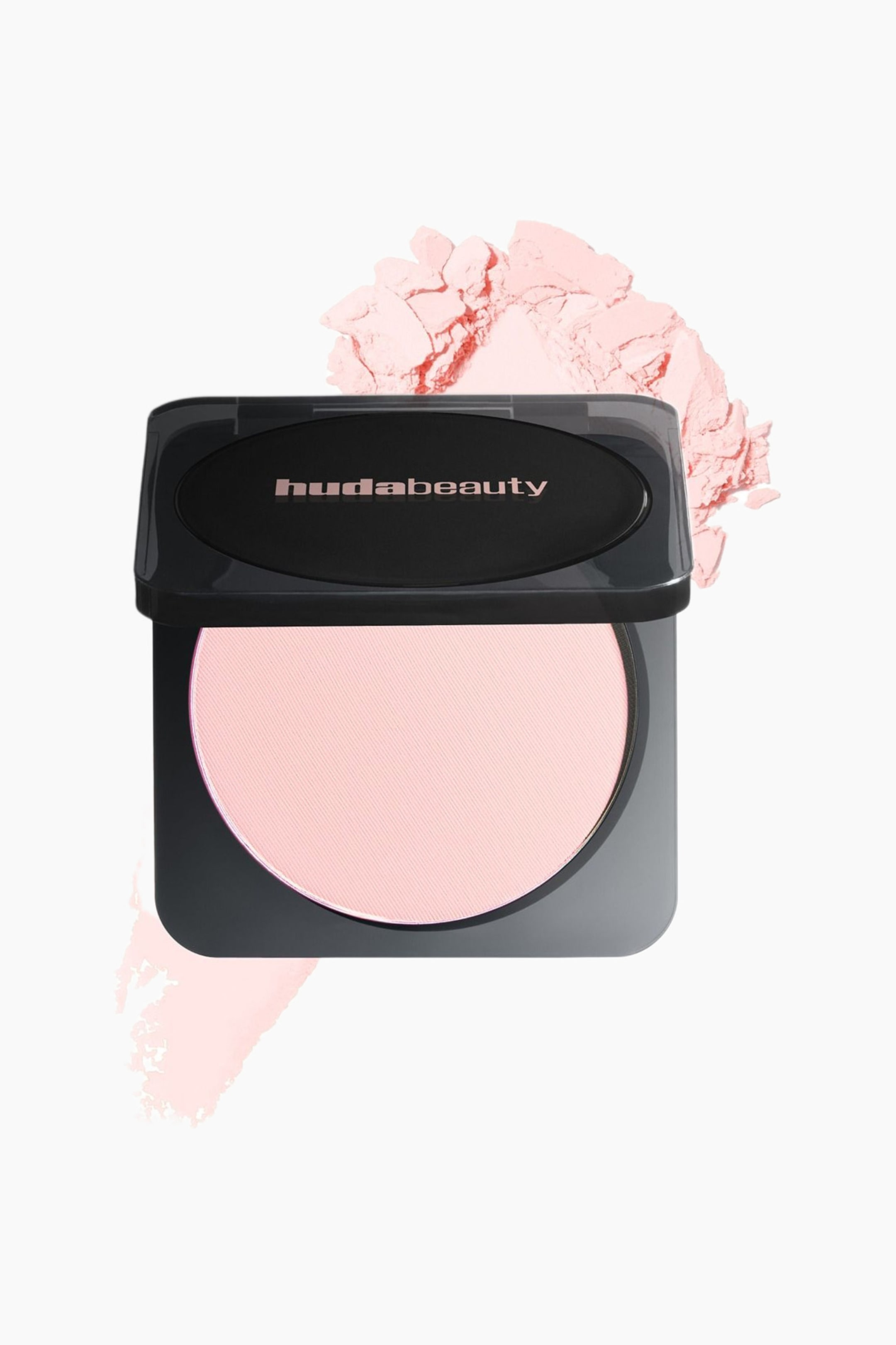 Visa större bild: Ett hudabeauty kompaktpuder visar ett svart fodral med ett delvis öppet gångjärnslock, något vinklat åt vänster. Inuti syns ett runt, ljust rosa pressat puder med en subtil diagonal textur.