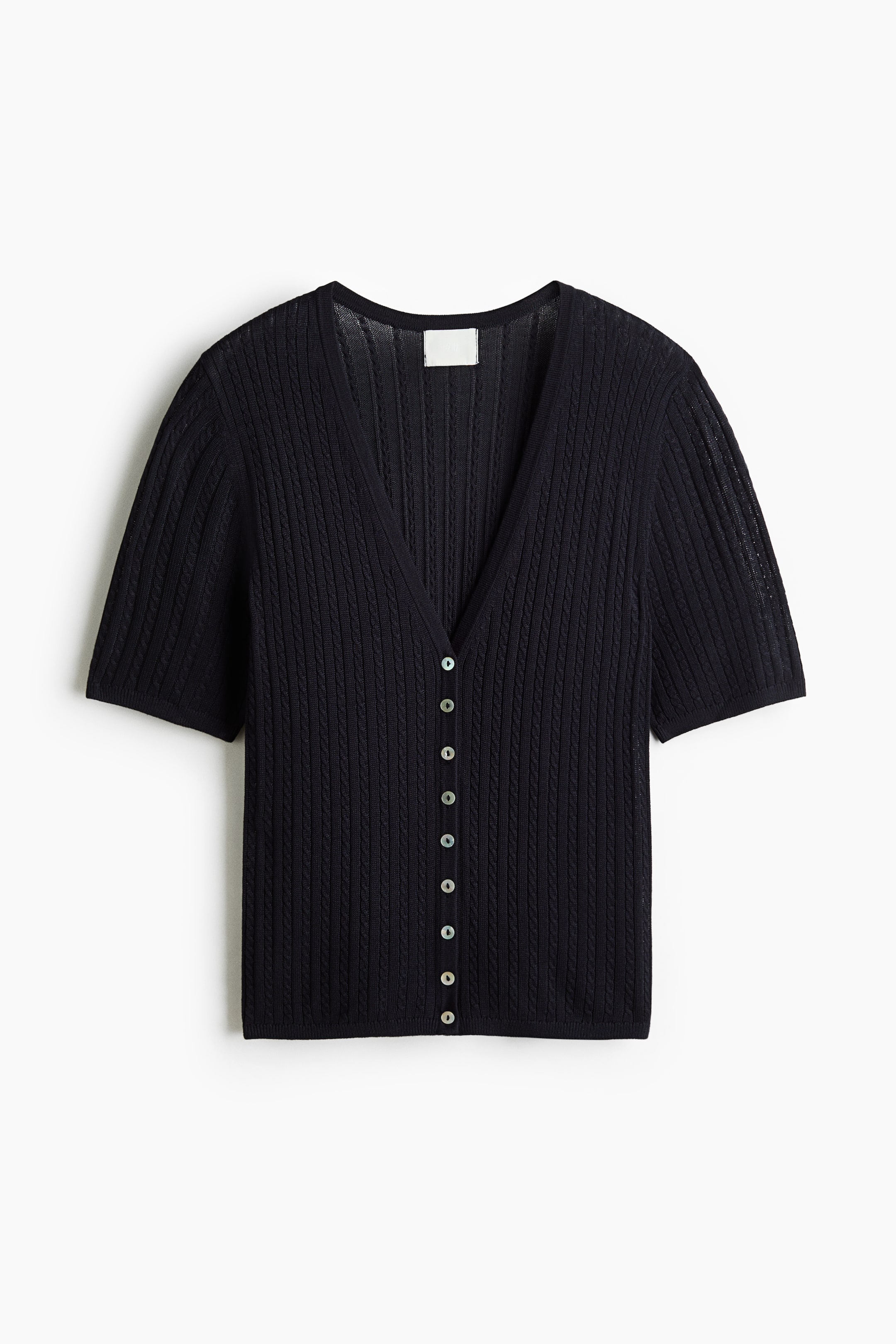 Xem ảnh lớn hơn: Một chiếc áo cardigan dệt kim màu đen tay ngắn được chụp từ phía trước, với cổ chữ V khoét sâu và họa tiết sọc dọc gân nổi. Thiết kế có phần cài nút phía trước gồm chín nút nhỏ màu sáng.