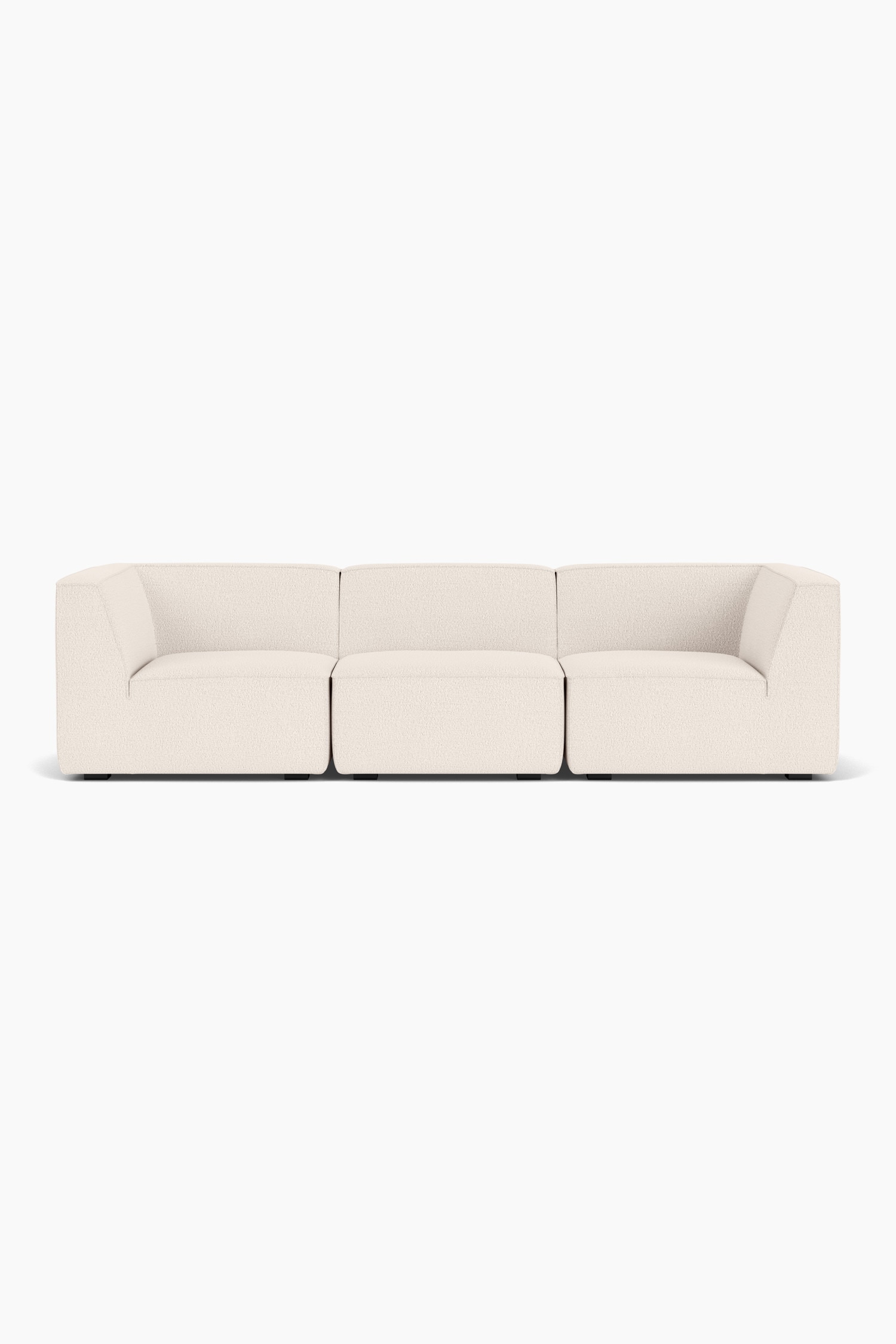 Ein niedriges modulares Sofa, bezogen mit einem strukturierten BouclÃ©-Stoff in Off-White, ist nach rechts ausgerichtet und prÃ¤sentiert seine klarlinigen, abgerundeten Kissen. Das Sofa zeigt Paspelnaht-Details entlang der Kanten seiner weichen Sitz- und RÃ¼ckenlehnenbereiche.