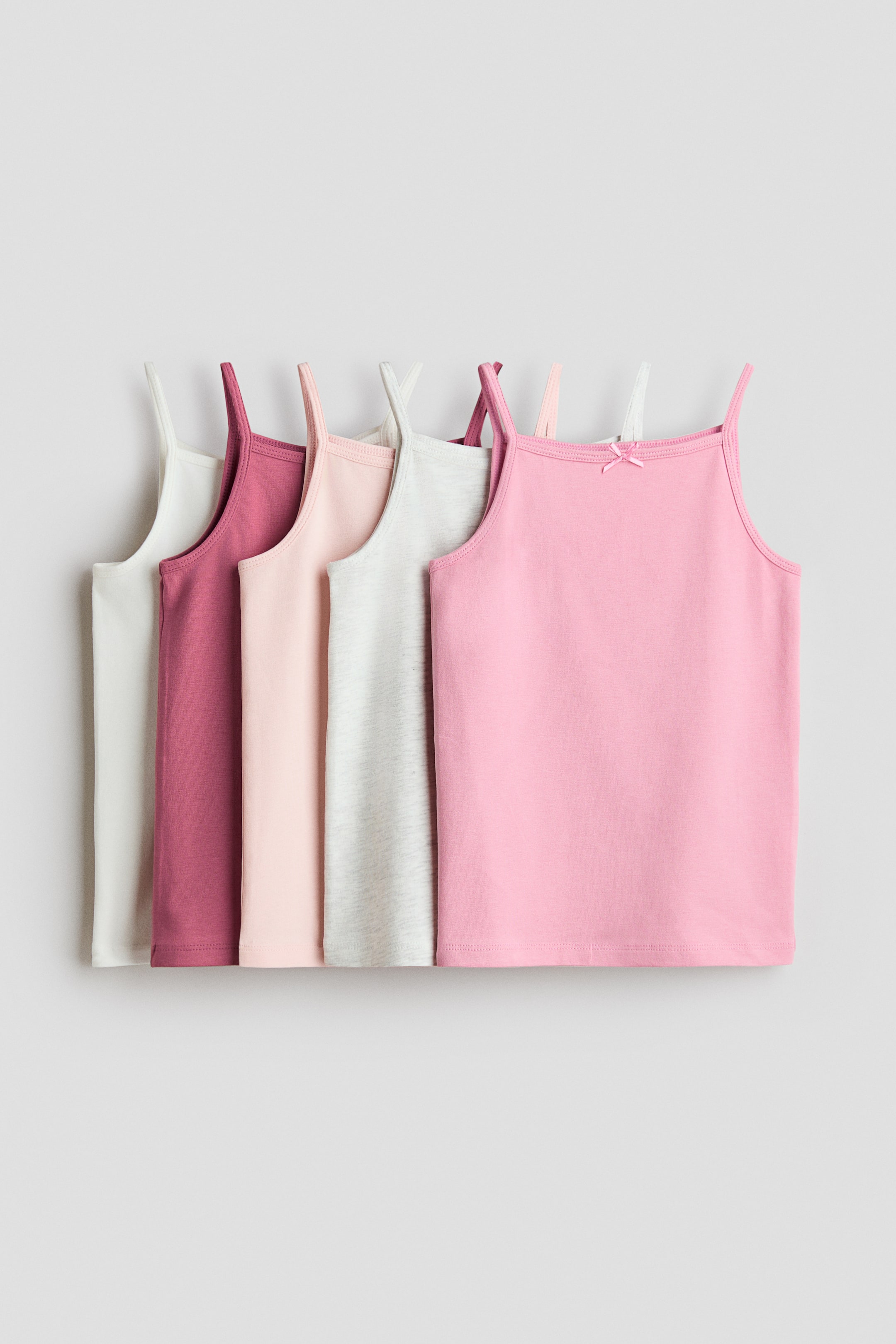 Agrandir l'image: Cinq débardeurs en jersey de coton doux sont présentés de face, chacun arborant un décolleté carré, de fines bretelles et un nœud décoratif en satin, visible sur le décolleté du débardeur rose. Les débardeurs sont disponibles en blanc, bordeaux, rose clair, gris chiné clair et rose.