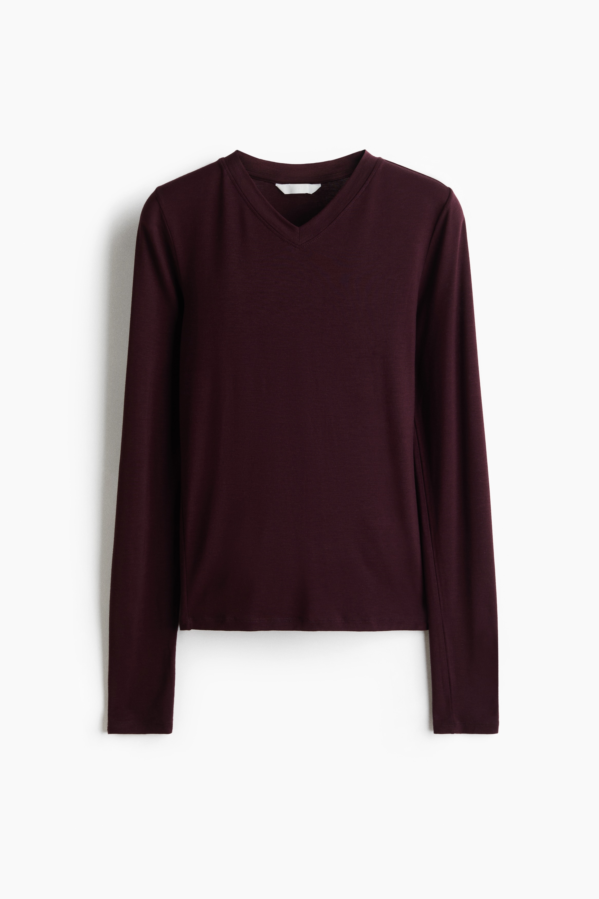 The model is wearing a dark burgundy, long-sleeved jersey top with a V-neckline. The top has a close-fitting silhouette and a smooth, soft texture.