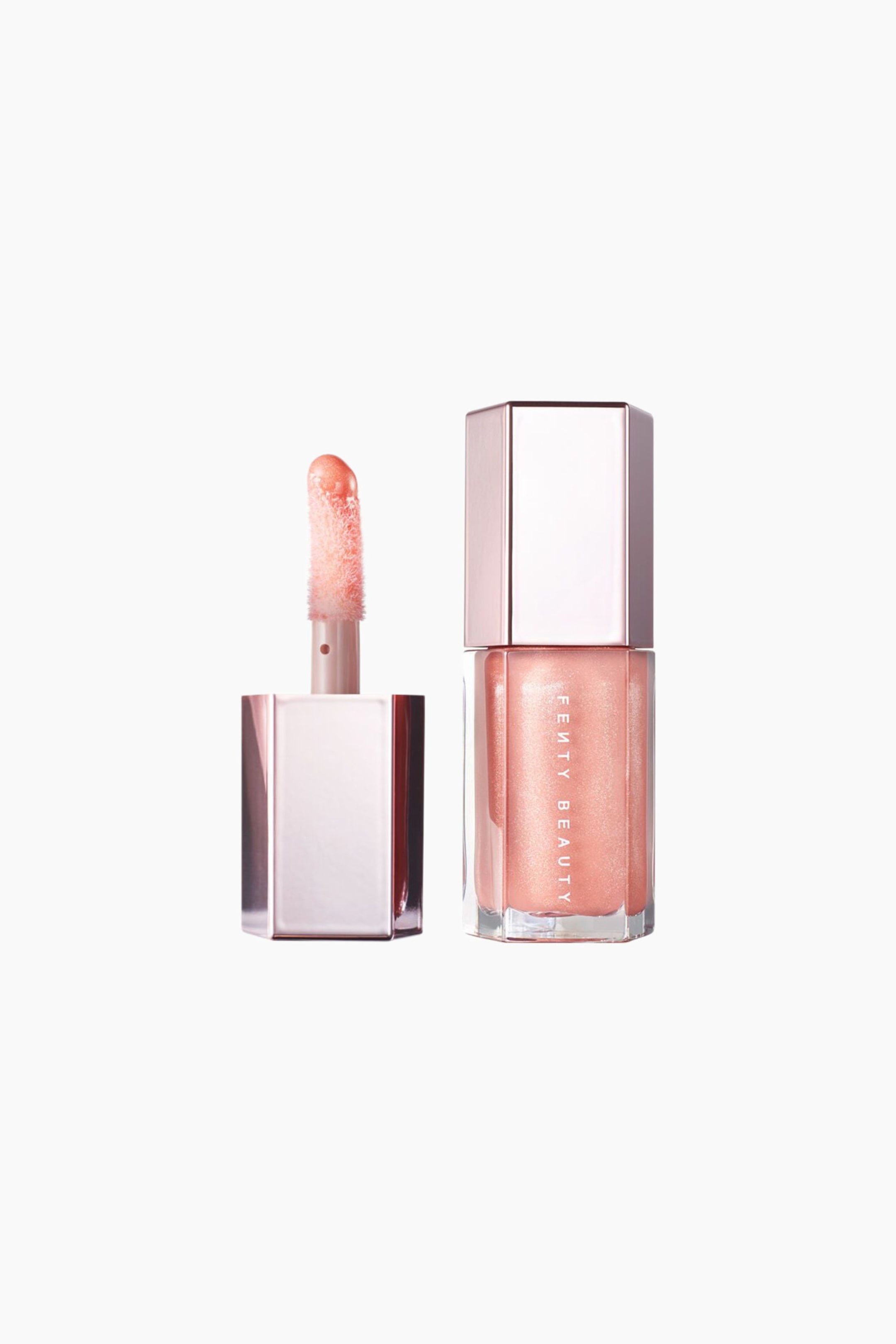 Visa större bild: Mini Gloss Bomb Universal Lip Luminizer visas i en genomskinlig sexkantig tub med skimrande persiko-rosa gloss och ett metalliskt roséguldfärgat lock. Bredvid tuben står det avskruvade metallocket, som håller applikatorn upprätt för att visa upp en mjuk doe foot-applikator täckt av gloss.