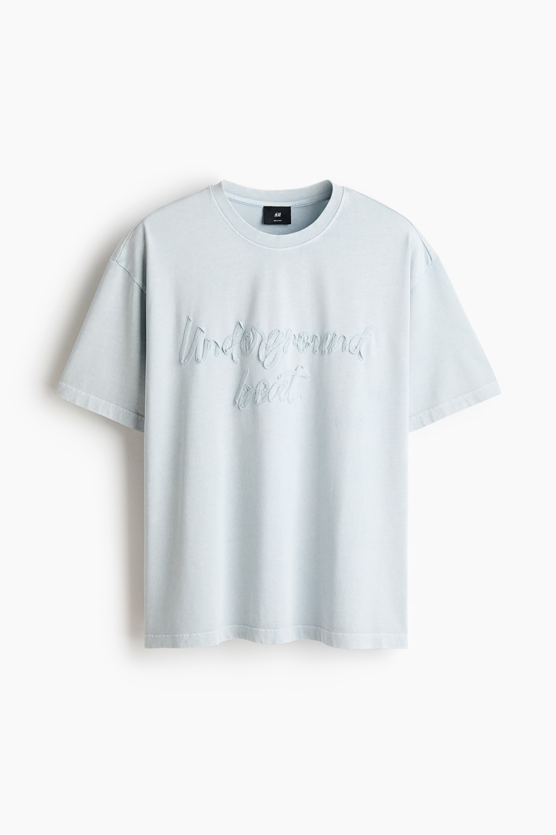 View larger image: A light blue t-shirt is lying flat, showcasing its front. It features a ribbed crew neck, short sleeves, and tonal embossed text on the chest that reads "Underground local."