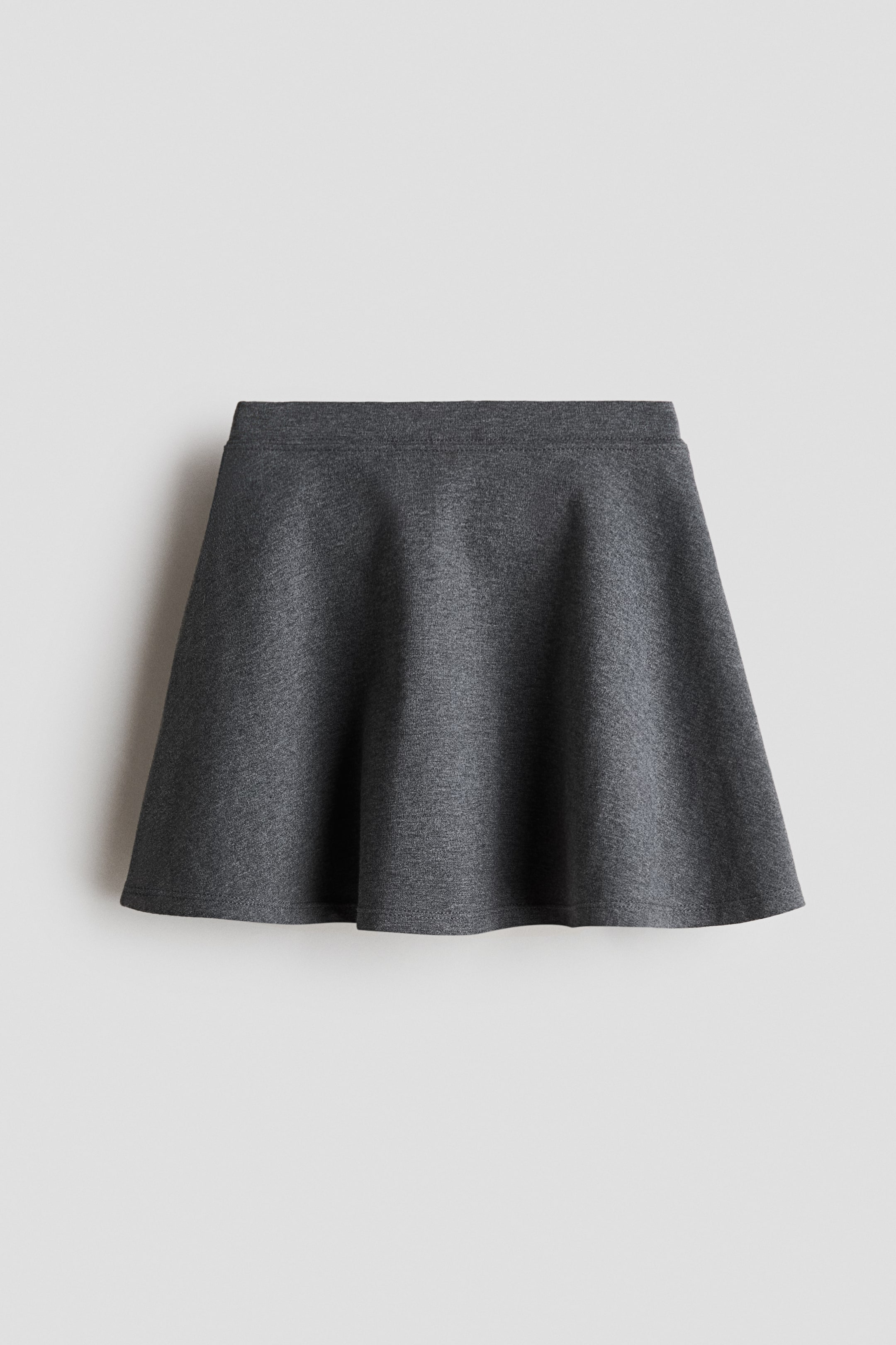 Agrandir l'image: Une jupe d'école gris foncé à hauteur de genou en jersey de coton doux est présentée de face, avec une taille élastiquée recouverte et un ourlet évasé.