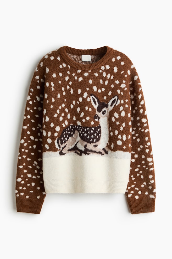 Ein brauner Strickpullover mit langen Ãrmeln ist von vorne zu sehen und prÃ¤sentiert ein durchgehendes weiÃes Sprenkelmuster. In der Mitte befindet sich ein Motiv eines gefleckten Hirsches, der auf einem einfarbig weiÃen unteren Einsatz ruht, wobei gerippte Details den Rundhalsausschnitt, die ÃrmelbÃ¼ndchen und den Saum zieren. - 1