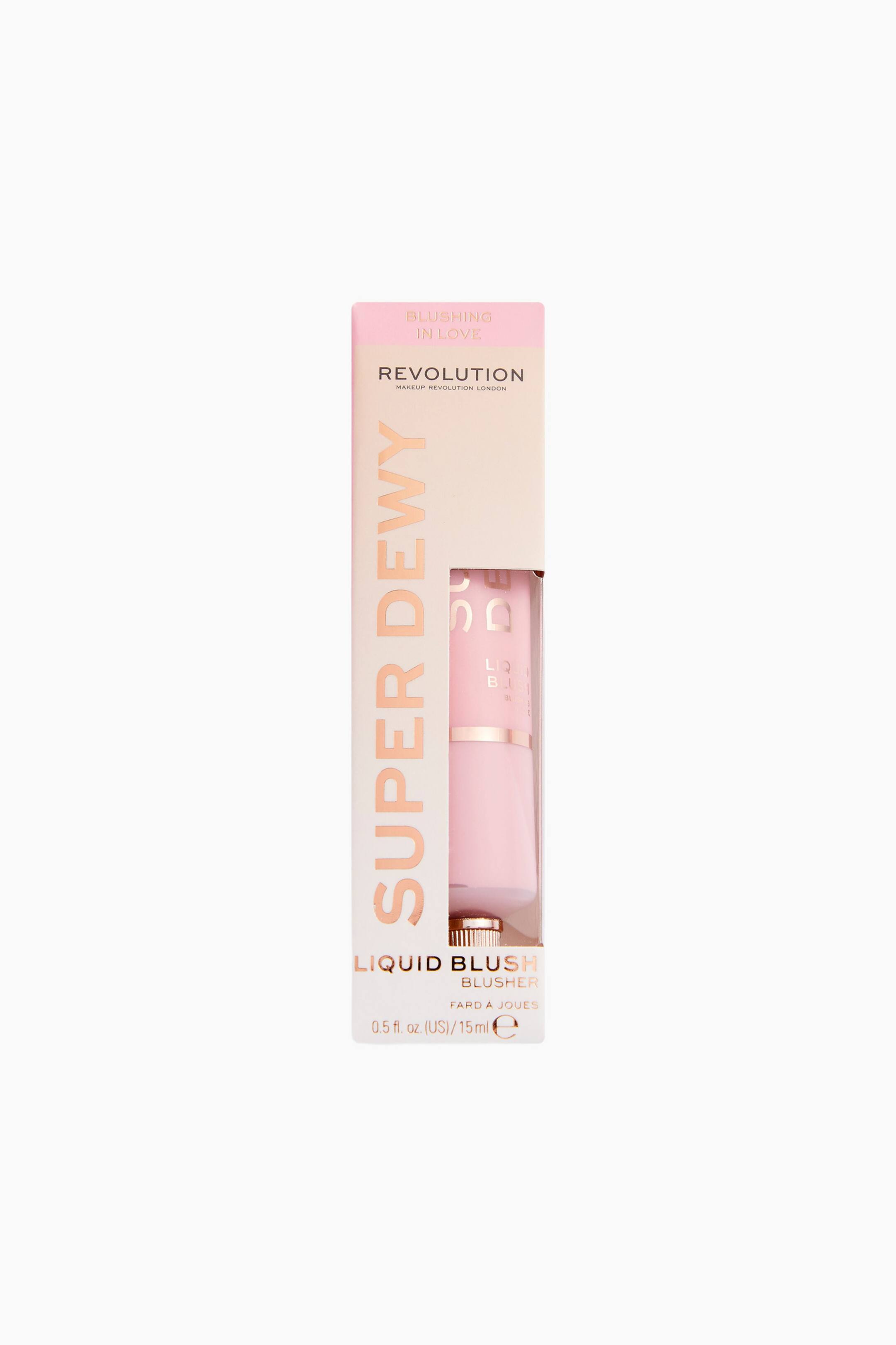 Größeres Bild ansehen: Der Superdewy Liquid Blush steht aufrecht in seiner hellrosa Kartonverpackung, die über einen vertikalen Ausschnitt verfügt und die hellrosa Squeeze-Tube im Inneren zeigt. Auf der nach vorne ausgerichteten Box ist links vertikal die Aufschrift „SUPER DEWY“ in Roségold zu sehen, während sich das „REVOLUTION“-Branding nahe der Oberseite befindet.