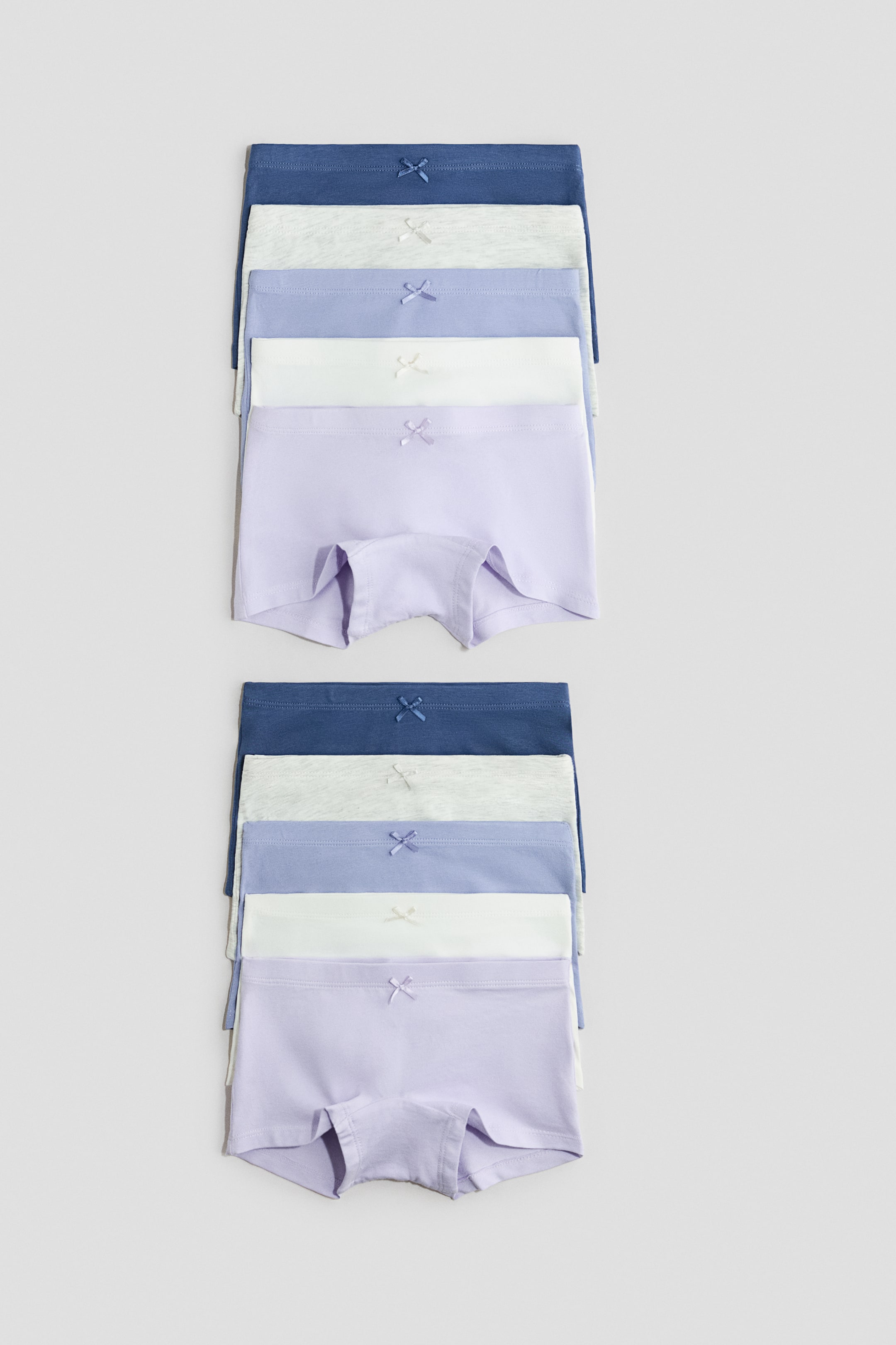 View larger image: "Dalawang tambak ng boxer briefs ang nakikita, bawat tambak ay nagpapakita ng limang pares sa iba't ibang lilim ng asul, abo, lila, at puti. Ang bawat pares na nakaharap ay gawa sa malambot na cotton jersey, na may elasticated waist at maliit na dekoratibong laso sa gitna."