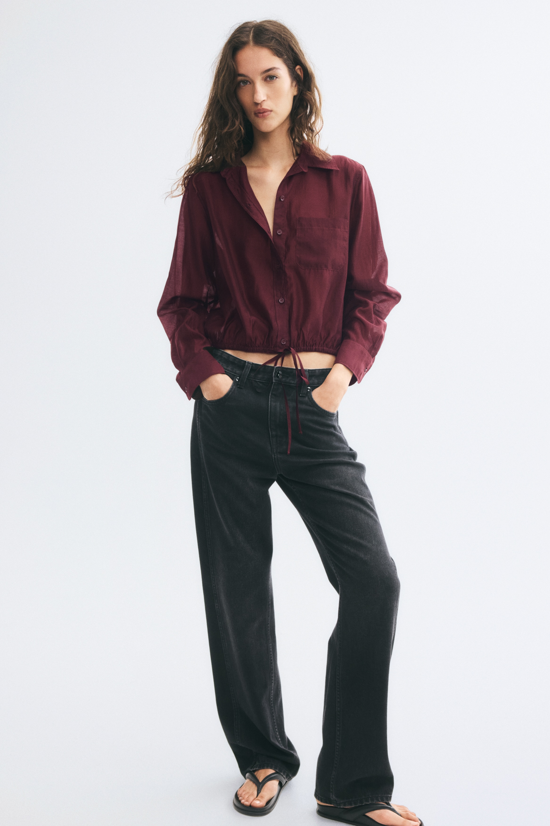 Má»t chiáº¿c Ã¡o sÆ¡ mi cÃ i nÃºt dÃ¡ng ngáº¯n mÃ u Äá» burgundy ÄÆ°á»£c chá»¥p tá»« phÃ­a trÆ°á»c, vá»i cá» nhá»n, má»t tÃºi Äáº¯p á» ngá»±c vÃ  tay dÃ i vá»i cá» tay rá»ng. Pháº§n gáº¥u Ã¡o ÄÆ°á»£c bo chun cÃ¹ng dÃ¢y rÃºt máº£nh Äá»ng mÃ u á» giá»¯a.