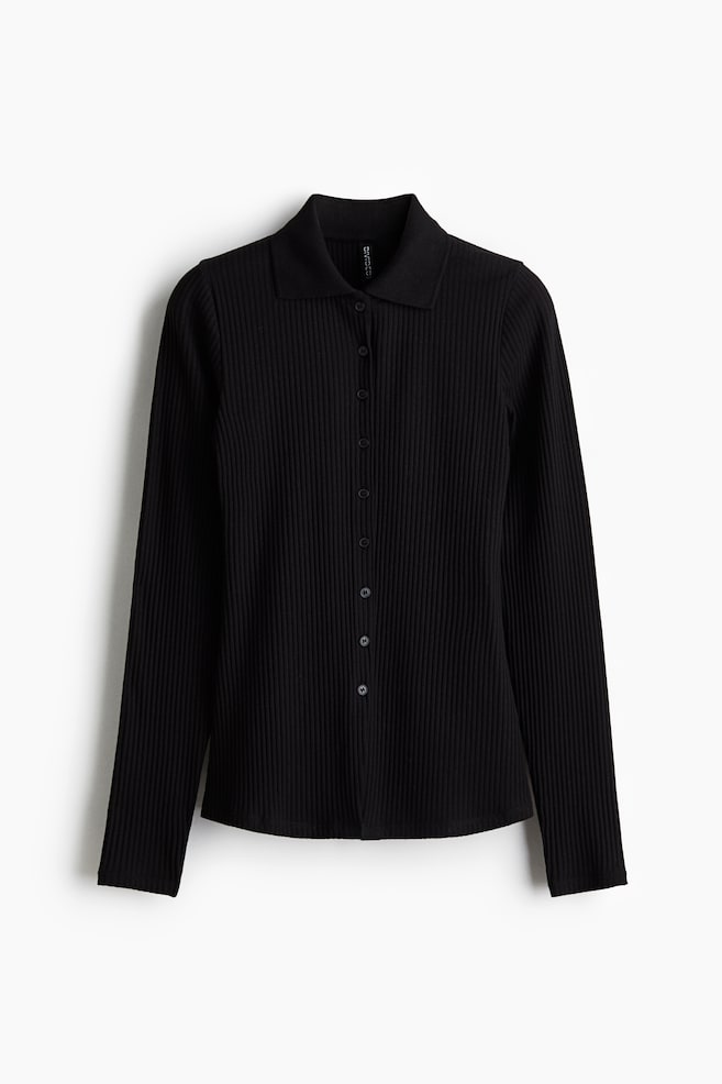 En sort tætsiddende cardigan præsenteres fra FRONTEN, med en ribbet jersey tekstur og en spids krave. Den er designet med en knaplukning foran med små sorte knapper og lange ærmer. - 1
