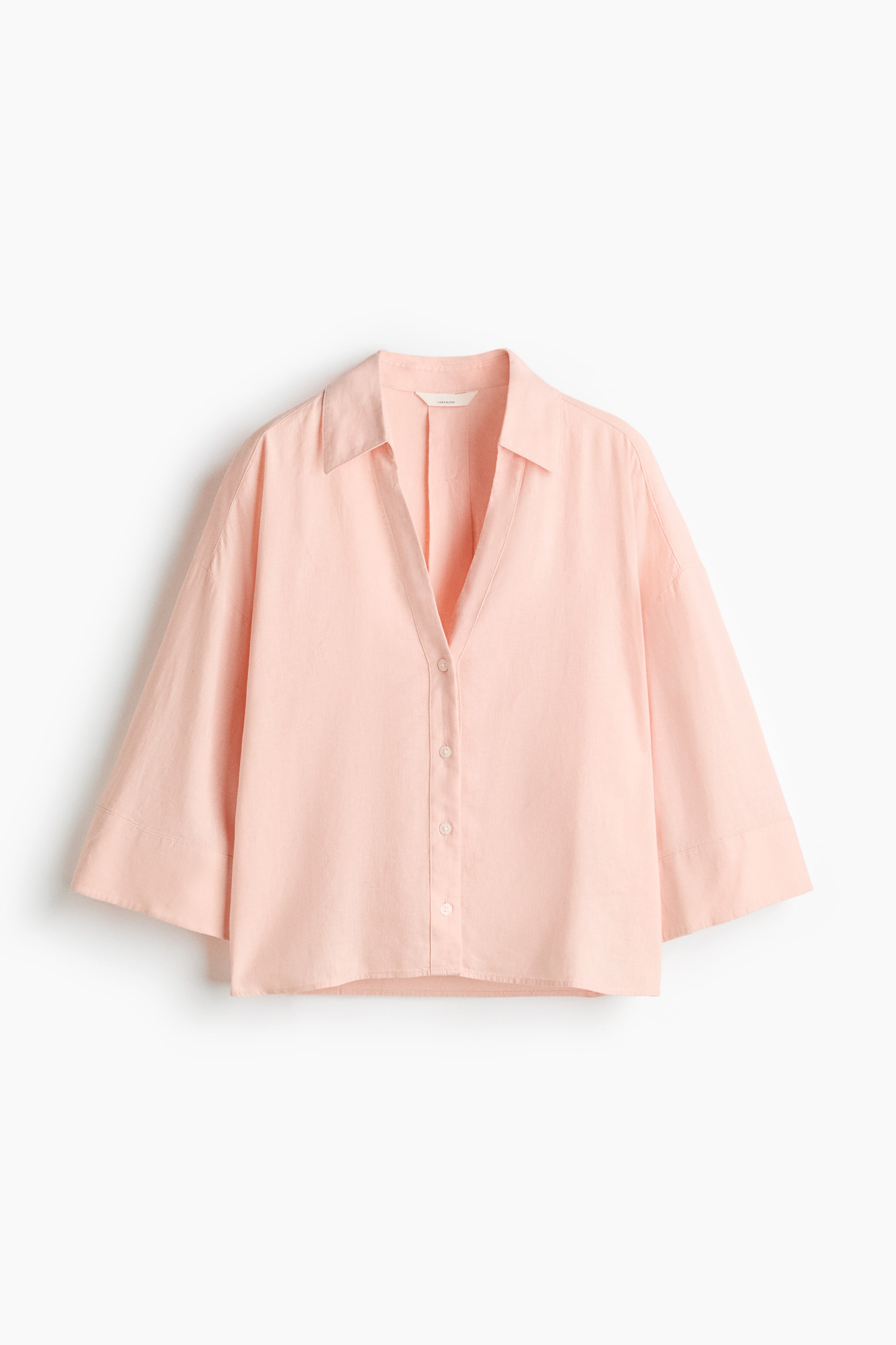 Ver imagen más grande: Una camisa rosa claro presenta su parte frontal, con un cuello abierto, un escote en V y una tapeta completa de botones a juego. Está diseñada con mangas anchas hasta el codo y un ajuste relajado.