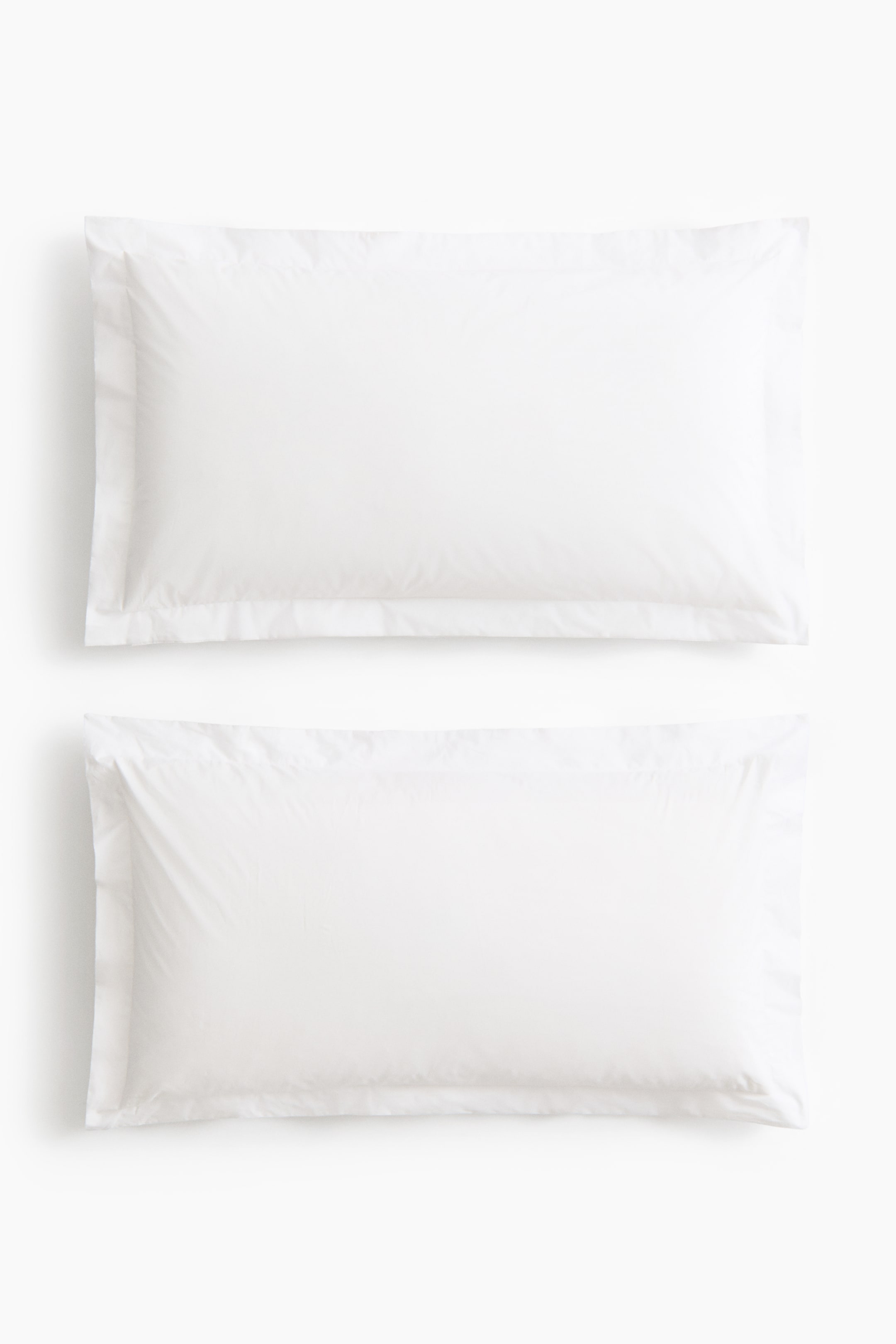 View larger image: Two white rectangular pillowcases lie flat, each featuring a wide flanged border around its edges.