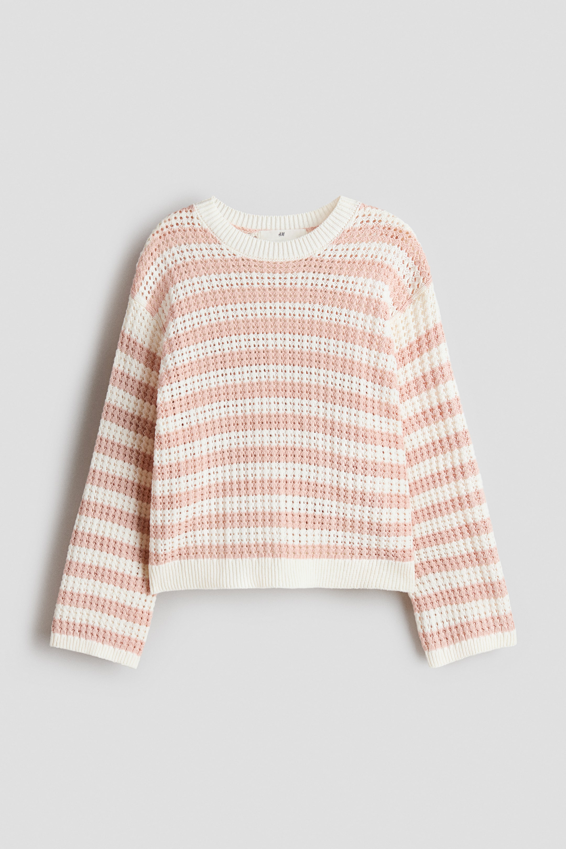 View larger image: A white and light pink striped sweater is shown from the front, featuring horizontal stripes in a waffle knit texture, a crew neck, and ribbed cuffs and hem.