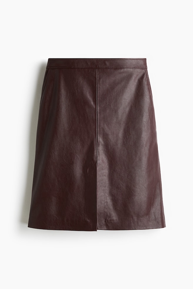 A dark reddish-brown faux leather knee-length skirt is presenting as FRONT. It is featuring a flat waistband and diagonal side pockets. A central vertical seam is running down the front, opening into a slit above a straight-cut hem. - 1