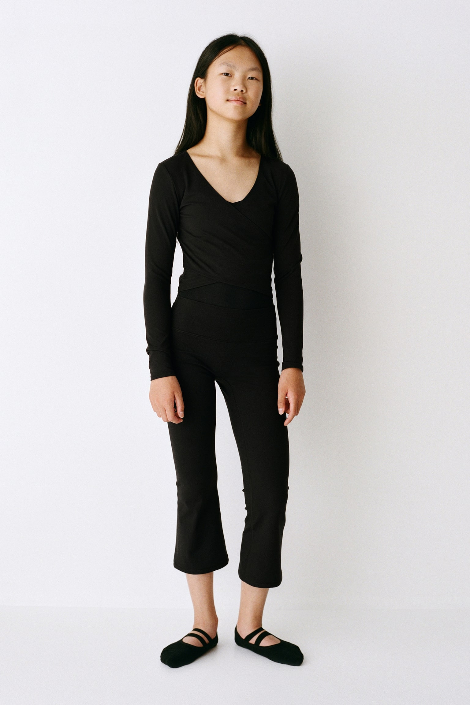 A pair of black cropped trousers, shown from the front, featuring a wide, high-rise waistband and a fitted thigh that flares out slightly into a cropped, wide-leg silhouette. - 1