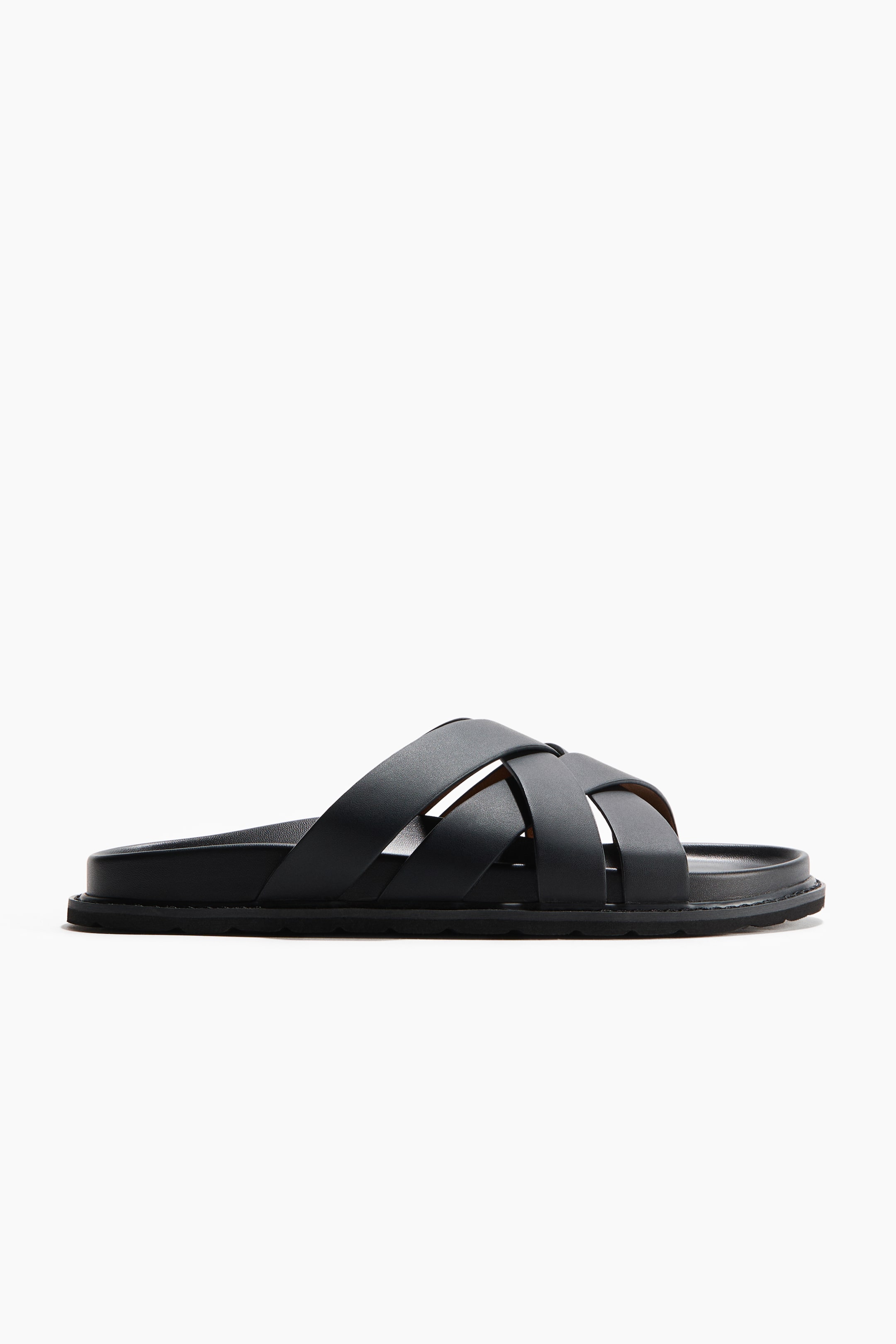 View larger image: The black sandal is shown in a side view. It features wide, crisscrossing straps over the instep and a thick, flat black sole with a subtly textured edge.