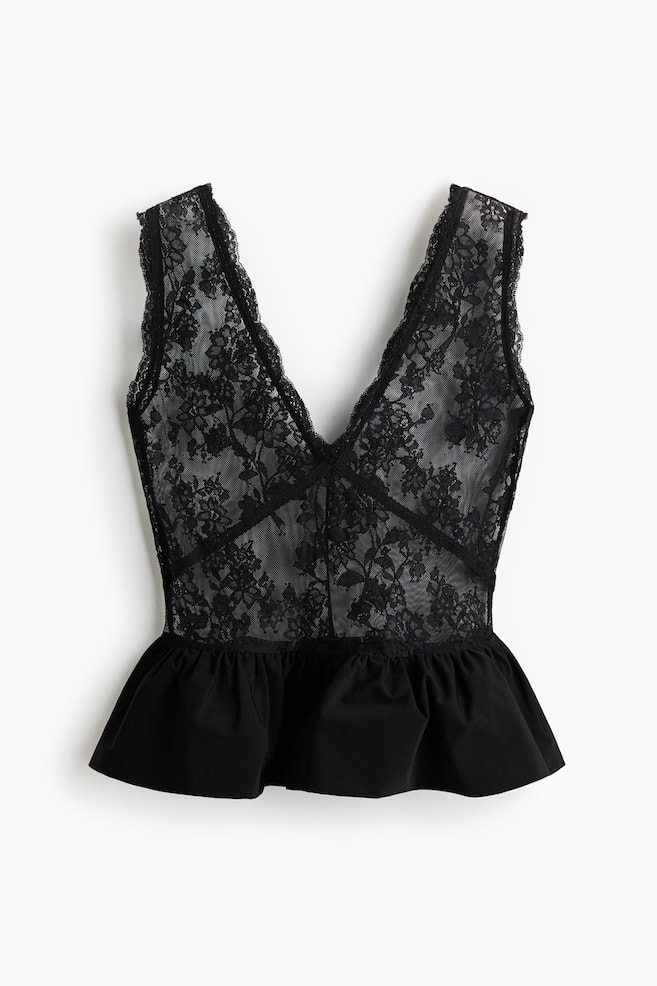 Een zwart kanten peplum top ligt plat en toont zijn vooraanzicht. Het heeft een diepe V-hals en een mouwloos ontwerp met kanten afwerking, en een doorschijnend bloemenkant lijfje dat overgaat in een solide zwarte geplooide peplum zoom bij de taille. - 1