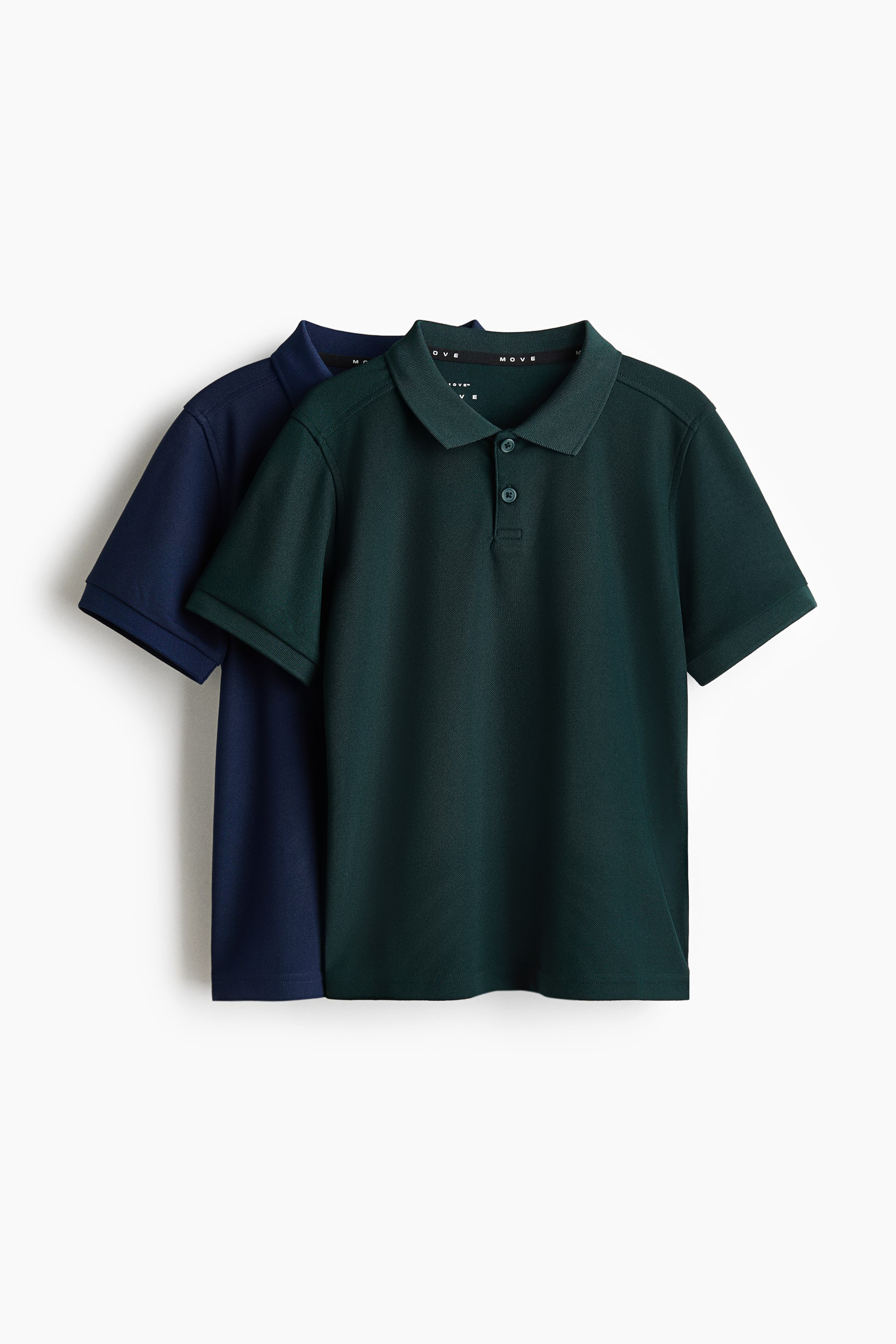 Grotere afbeelding bekijken: Twee regular fit sportpolo's worden gepresenteerd, met een donkergroen shirt iets naar voren geplaatst voor een donkerblauw shirt. De donkergroene polo aan de voorkant heeft een kraag met knoopsluiting, een placket met drie knopen en korte mouwen, waarbij de binnenste nekband van beide shirts het "MOVE"-logo toont.
