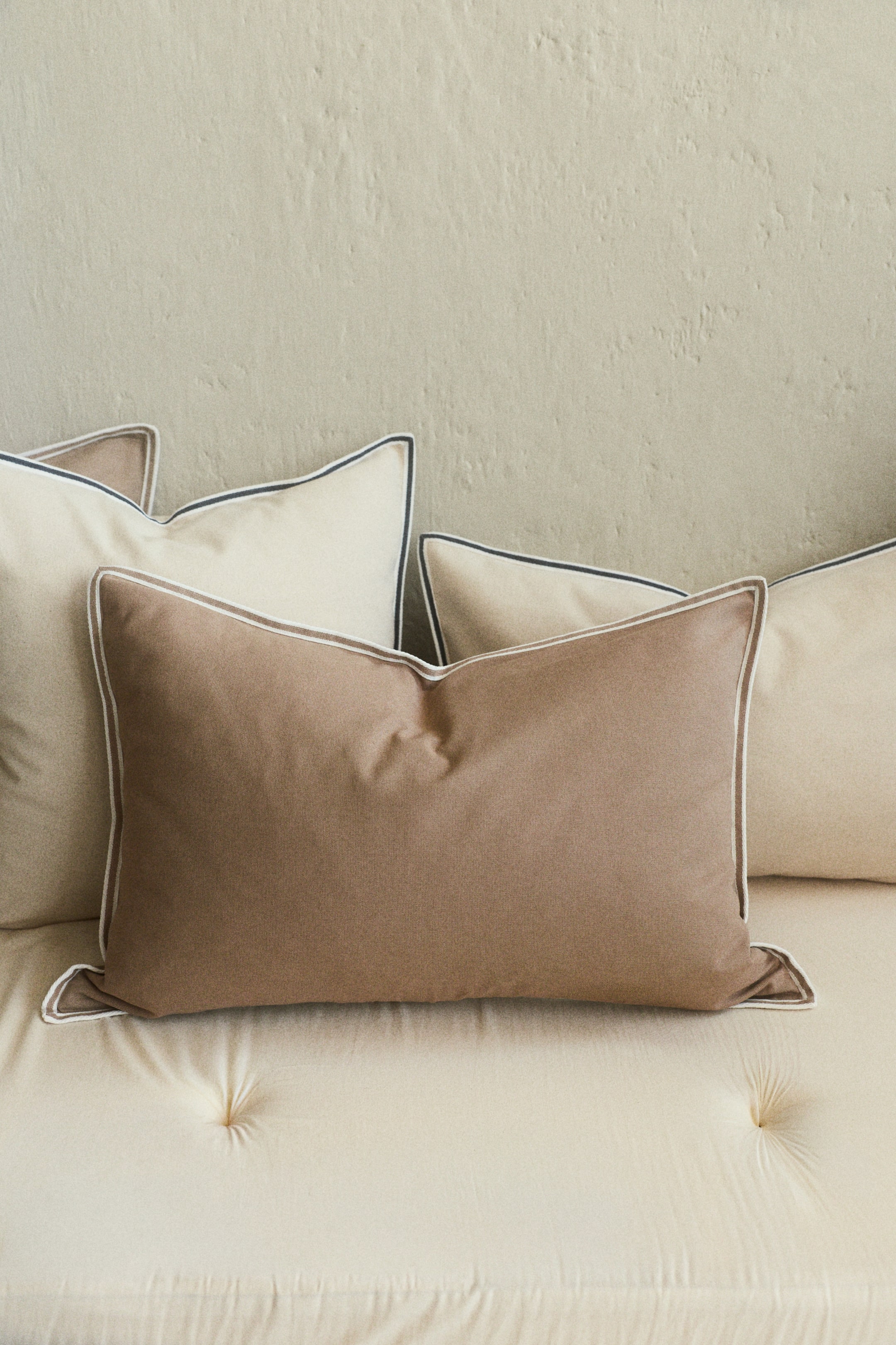 Agrandir l'image: Une housse de coussin rectangulaire en toile de coton marron est présentée de face, avec une bordure de couleur claire le long de tous ses bords.