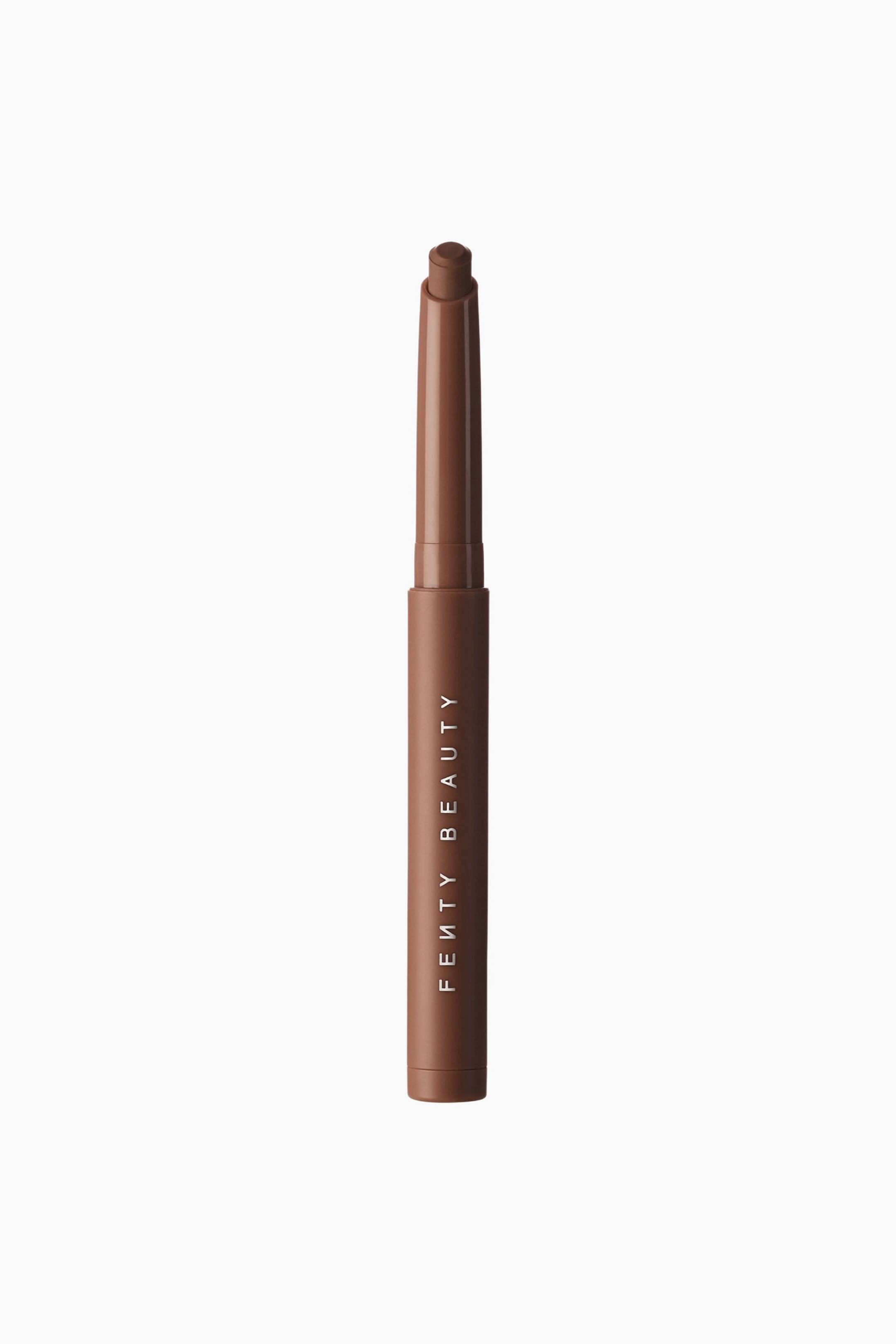 Se større billede: Shadowstix Longwear Eyeshadow Stick står lodret og fremviser sin matte brune hylster med brandnavnet "FENTY BEAUTY" trykt i hvide, lodrette bogstaver. Den uåbnede applikator afslører en blank brun hals og en matchende brun, fladtoppet cream eyeshadow-spids.