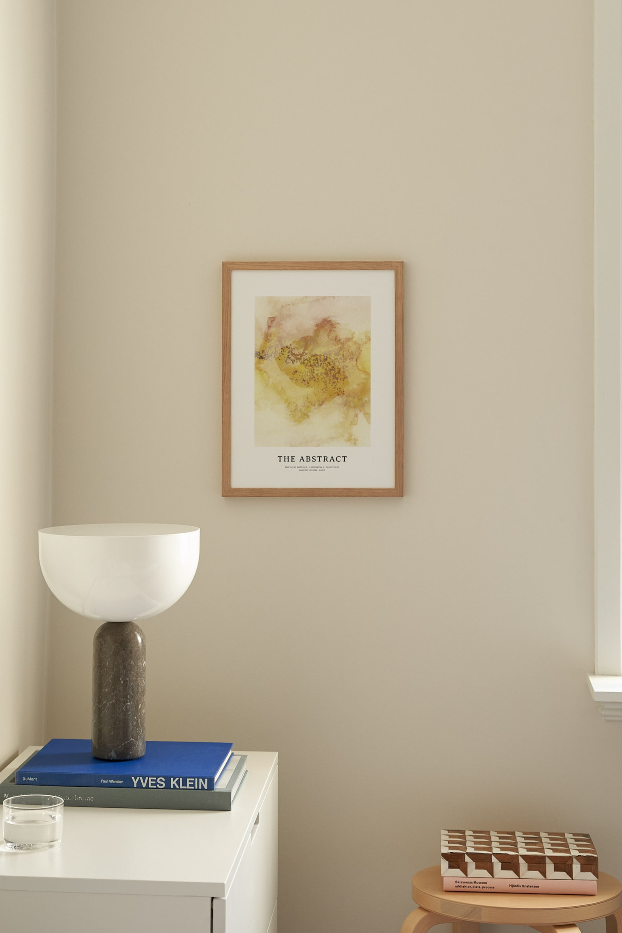 Grotere afbeelding bekijken: "The Abstract" ingelijste kunstprint toont een abstract ontwerp met gele, oranje en bruine tinten, met de titel "THE ABSTRACT" prominent weergegeven en kleinere tekst eronder. Het is ingekaderd in een lichtbruine houten lijst en hangt frontaal.