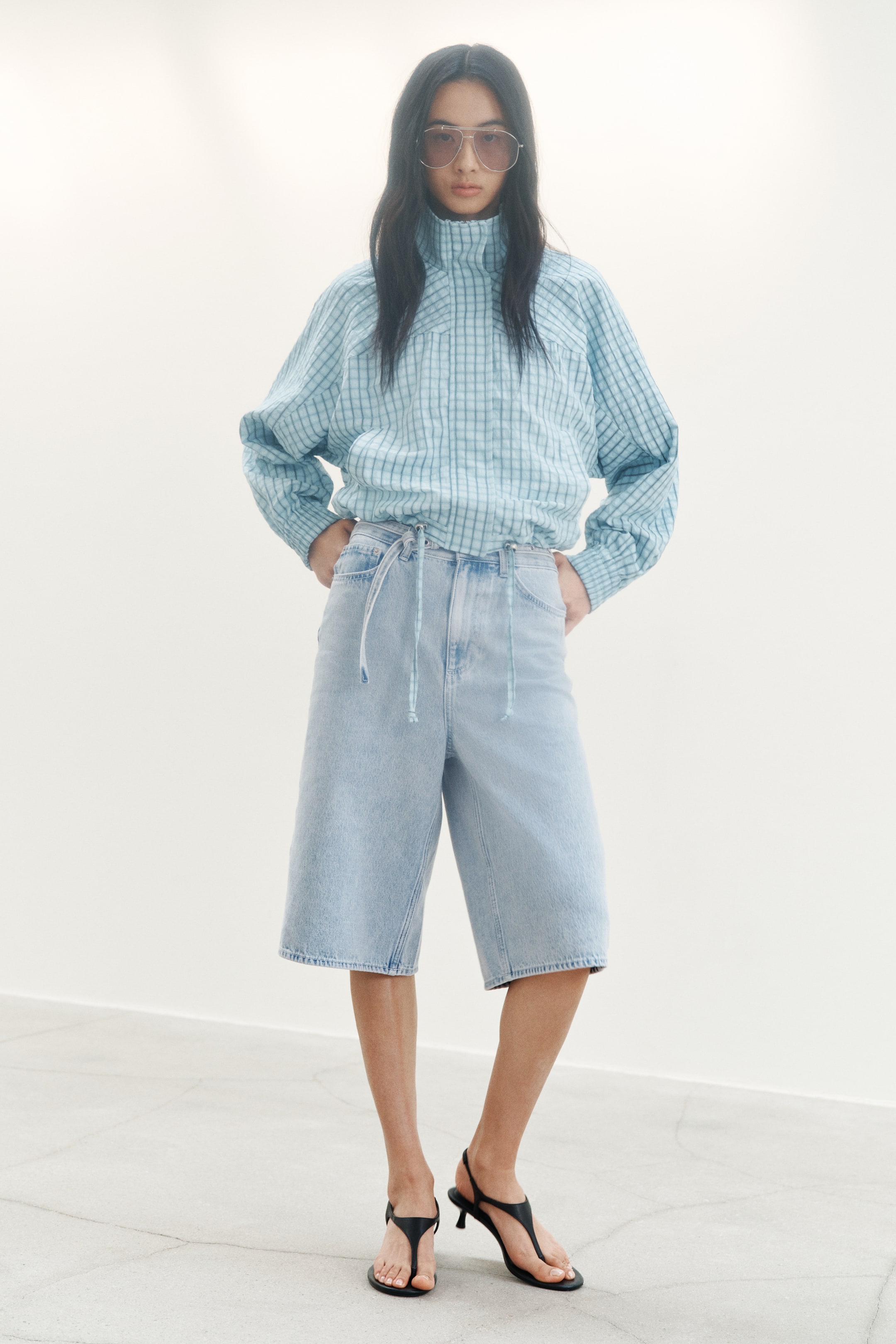 View larger image: Knee-length, 5-pocket shorts in light wash cotton denim are being worn by the model. The model is standing with hands on hips.