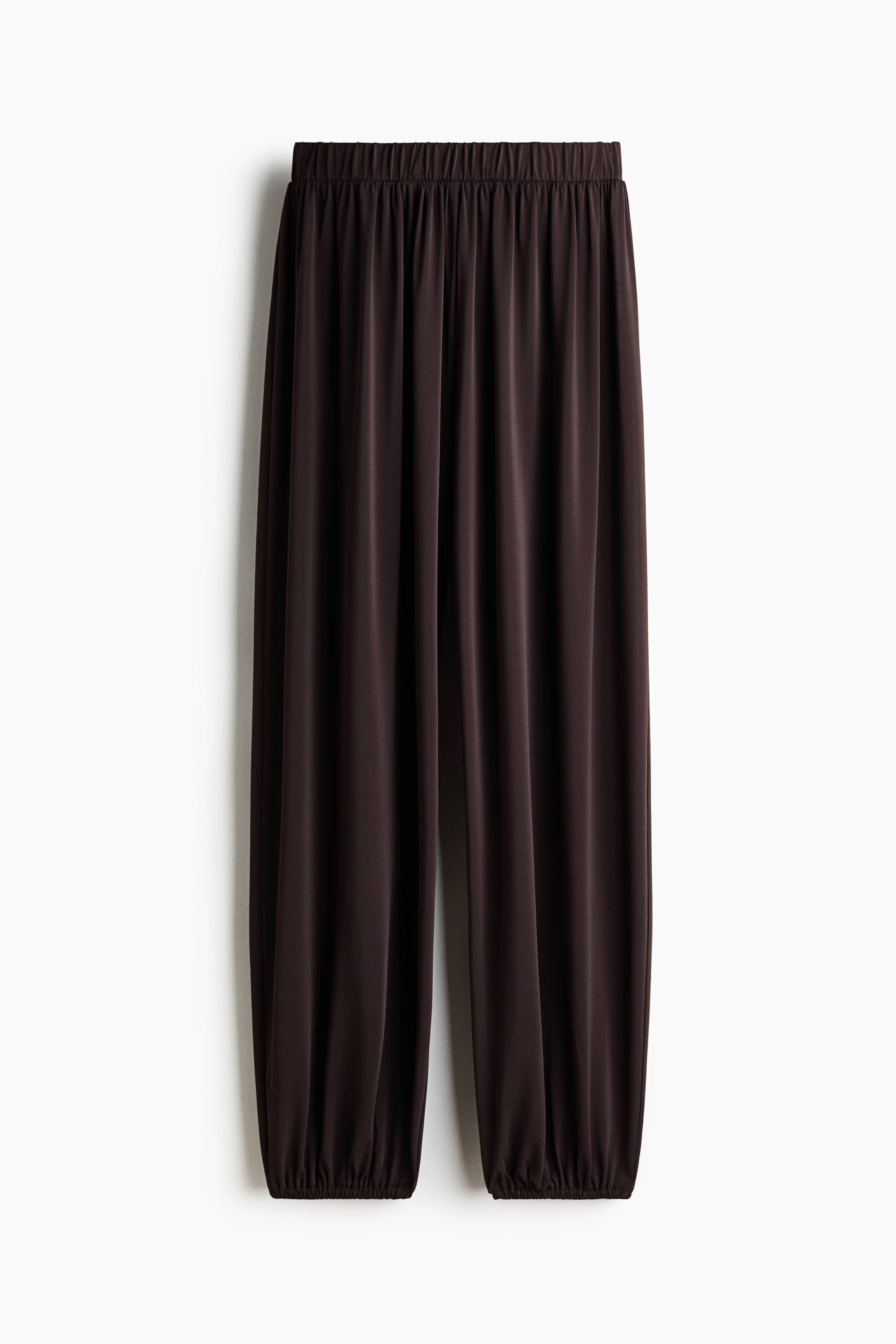 View larger image: Dark brown pants are displayed from the front, showcasing an elasticated waistband and gathered elasticated cuffs at the ankles.