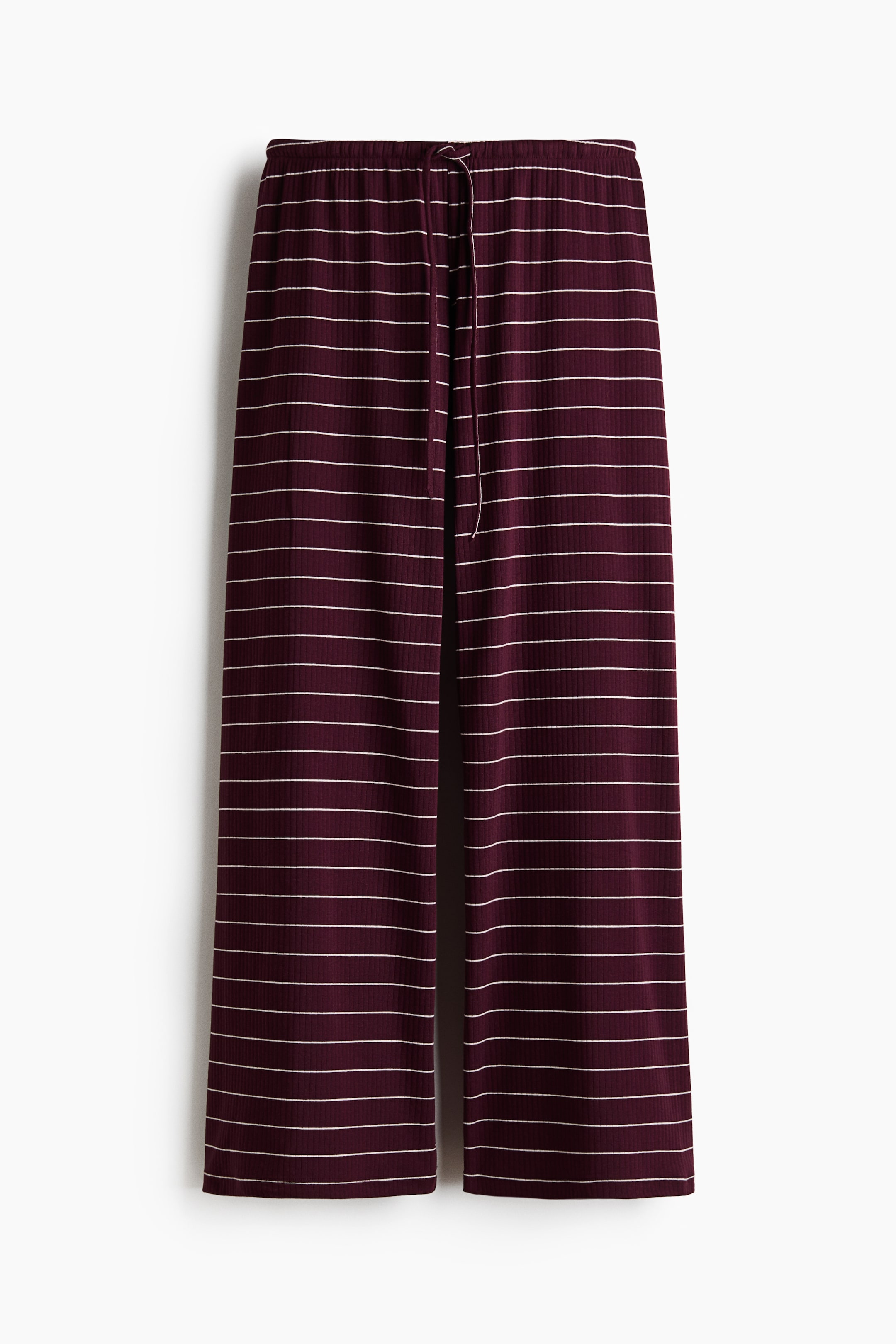 Agrandir l'image: Un pantalon ample et décontracté en jersey côtelé, composé d'un mélange de coton, est présenté à plat et de face, affichant une couleur pourpre foncé avec des rayures horizontales blanches, une taille élastiquée recouverte, et un cordon de serrage blanc étroit.