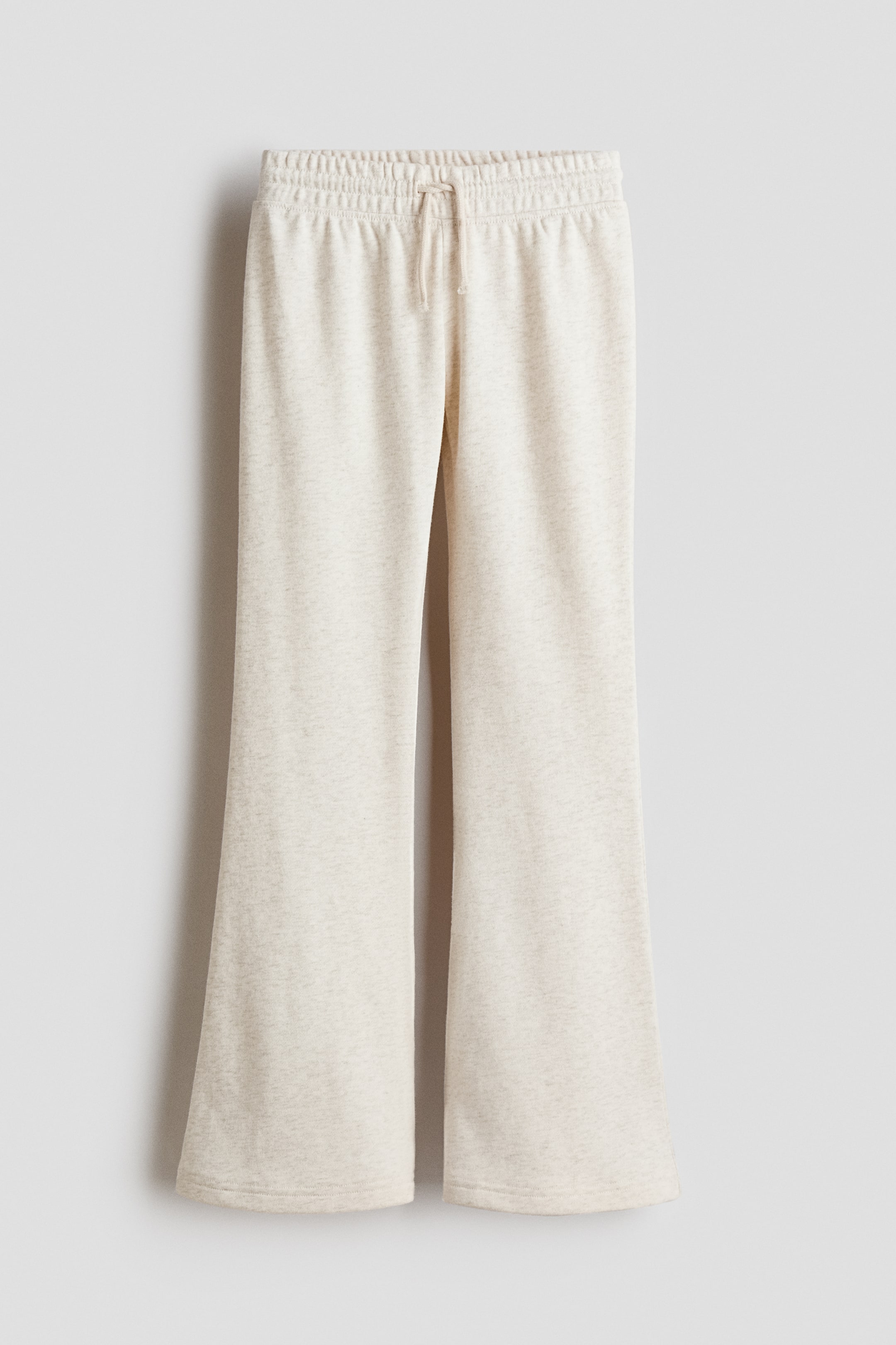 Voir une image plus grande: Le pantalon de jogging beige clair présente une taille élastique avec cordon de serrage et des jambes évasées, vu de face.