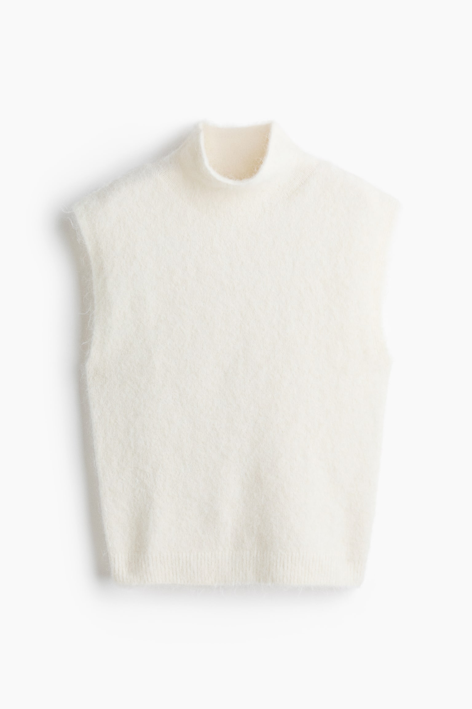 Un pull sans manches de couleur crème présente une texture tricotée duveteuse, un col montant et un ourlet inférieur côtelé. - 1