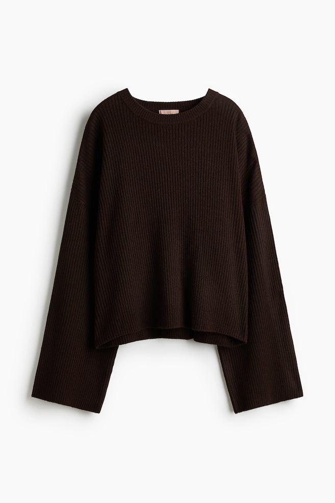 The dark brown ribbed knit jumper is laid flat and front facing, featuring a round neckline and long, wide sleeves with unbanded hems. - 1