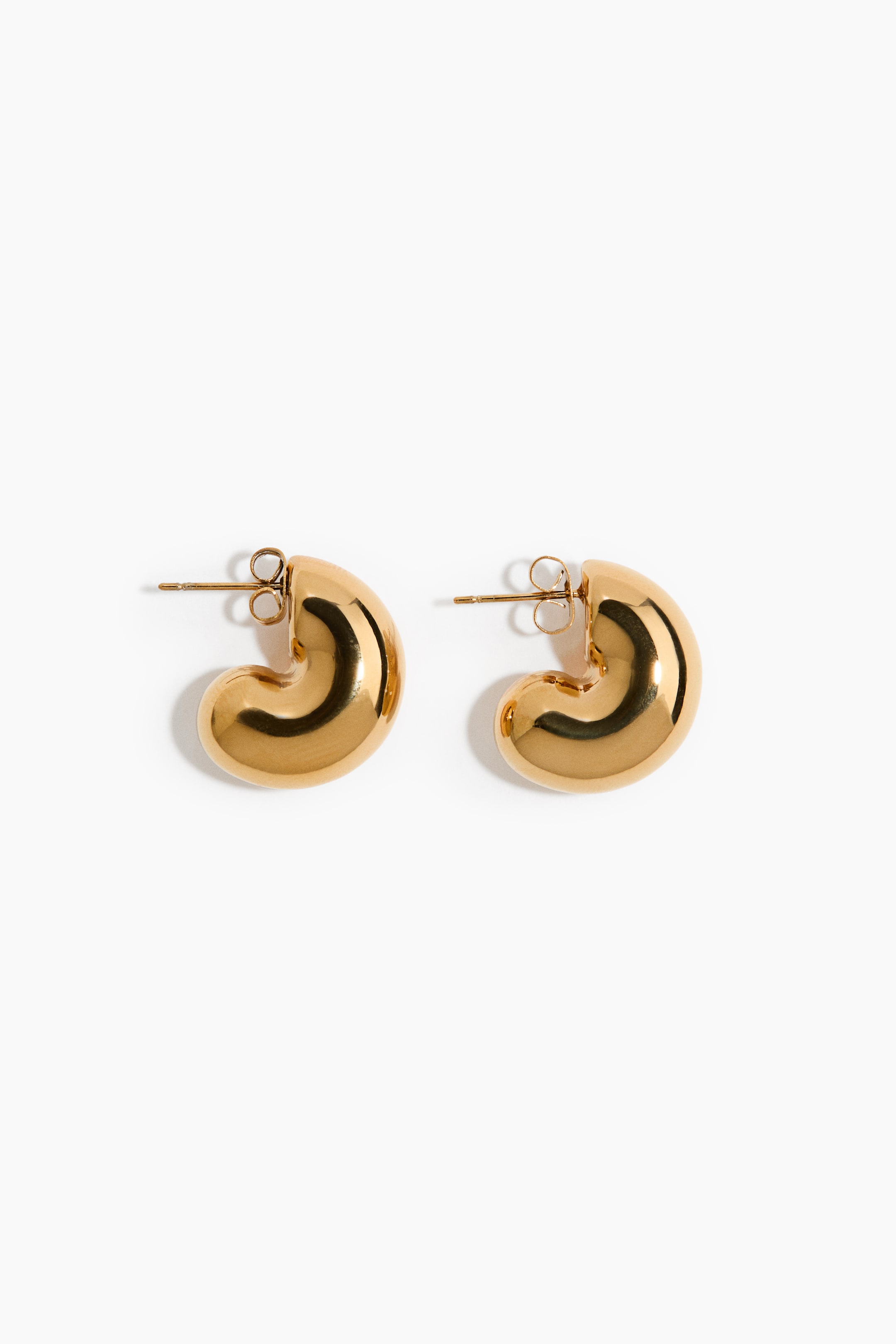 Agrandir l'image: Une paire de boucles d'oreilles à clous en or est présentée, chacune arborant un design en forme de C gonflé avec une finition lisse et réfléchissante. La tige du clou et le fermoir papillon sont visibles à l'arrière de chaque boucle d'oreille.