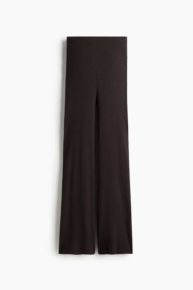 Dark brown wide-leg pants are featuring a ribbed knit fabric with subtle vertical lines. A wide, flat waistband is visible at the top, and a subtle center crease is running down the front of each leg. - 1