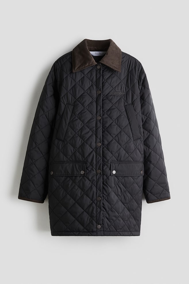 A black diamond-quilted jacket is presenting a brown corduroy spread collar and a front snap button closure. It includes two front flap pockets with snap closures, brown corduroy trim on the cuffs, and subtle dark embroidery on the chest. - 1