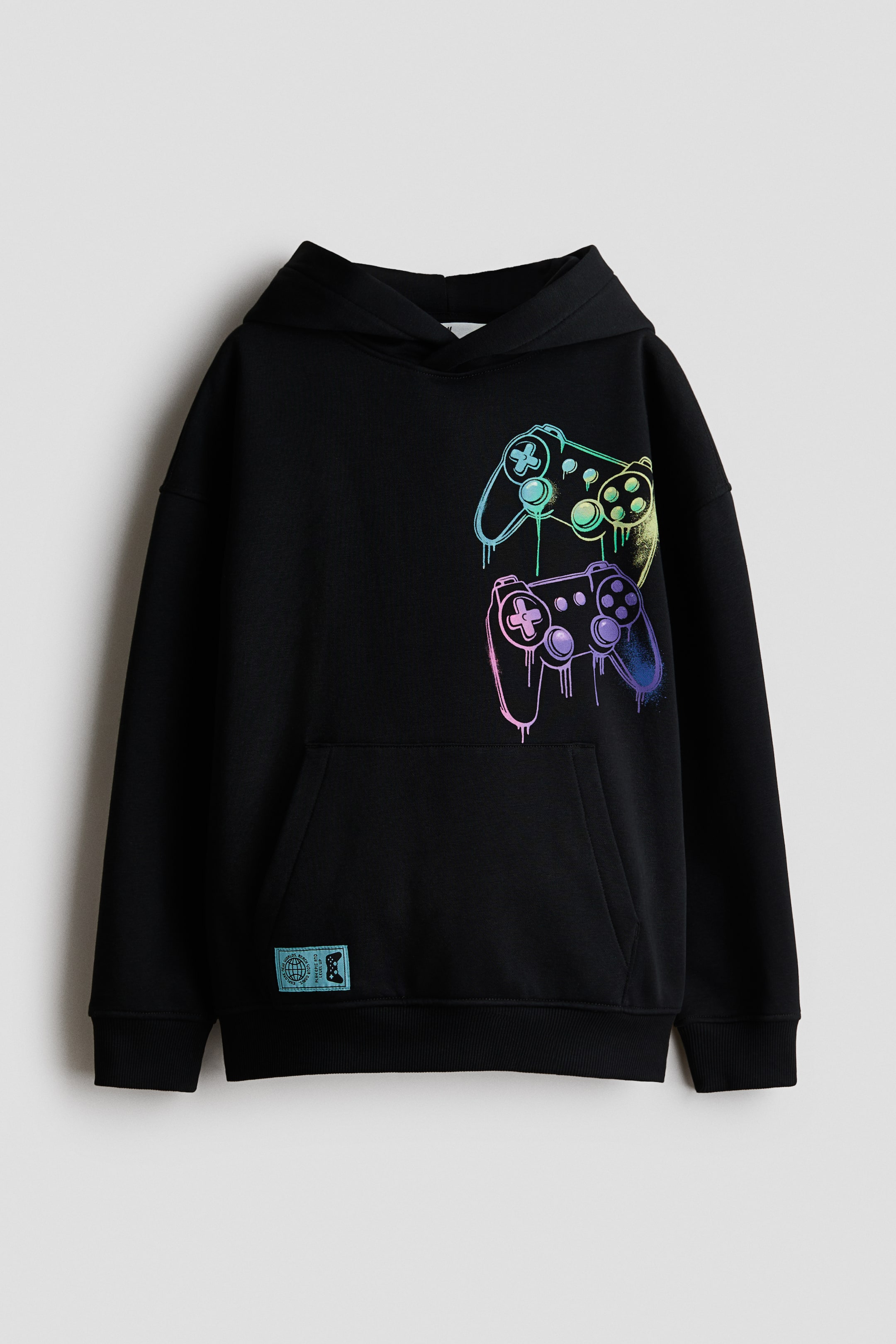 View larger image: The black loose-fit hoodie is positioned facing forward, showcasing a vibrant printed design of two video game controllers with a dripping effect on the front. It features a jersey-lined hood with a wrapover front, dropped shoulders, long sleeves, a kangaroo pocket, and ribbed cuffs and hem.