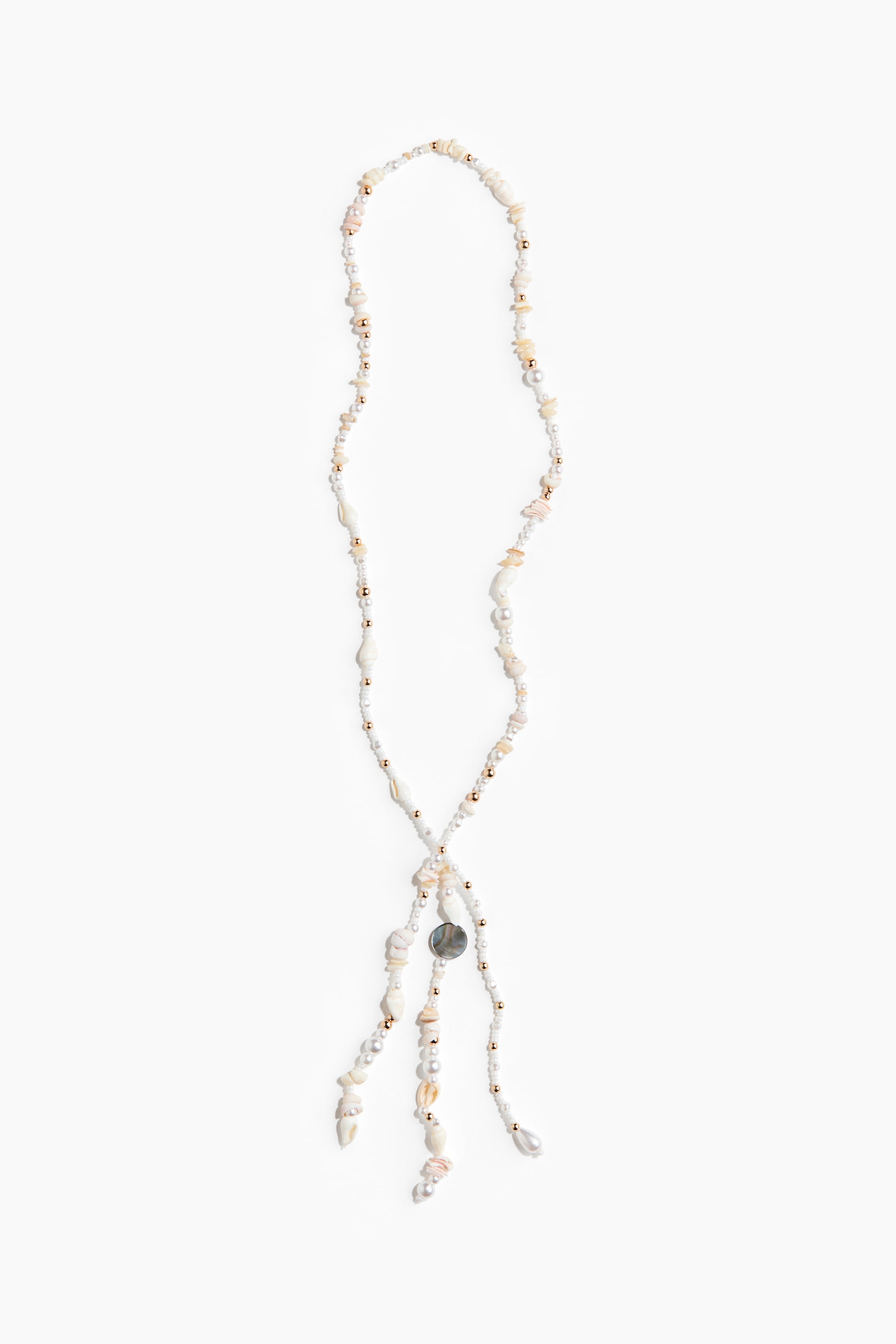 Ver imagen más grande: Un collar estilo lariat presenta pequeñas cuentas de semillas blancas, cuentas esféricas de tono dorado, piezas de concha natural irregulares y varias perlas blancas. El collar forma un lazo en su centro, donde se puede ver una concha circular gris oscuro iridiscente, con múltiples hileras de cuentas y conchas colgando.