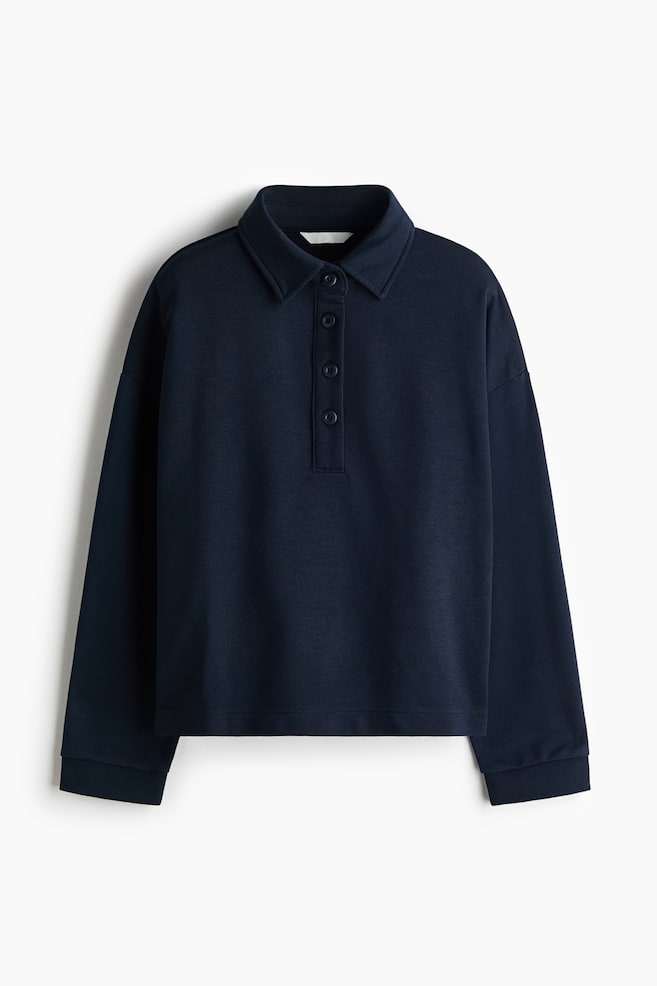 A navy long-sleeved top is presented front-facing. It features a spread polo collar and a four-button placket. The top is designed with dropped shoulders and wide cuffs. - 1